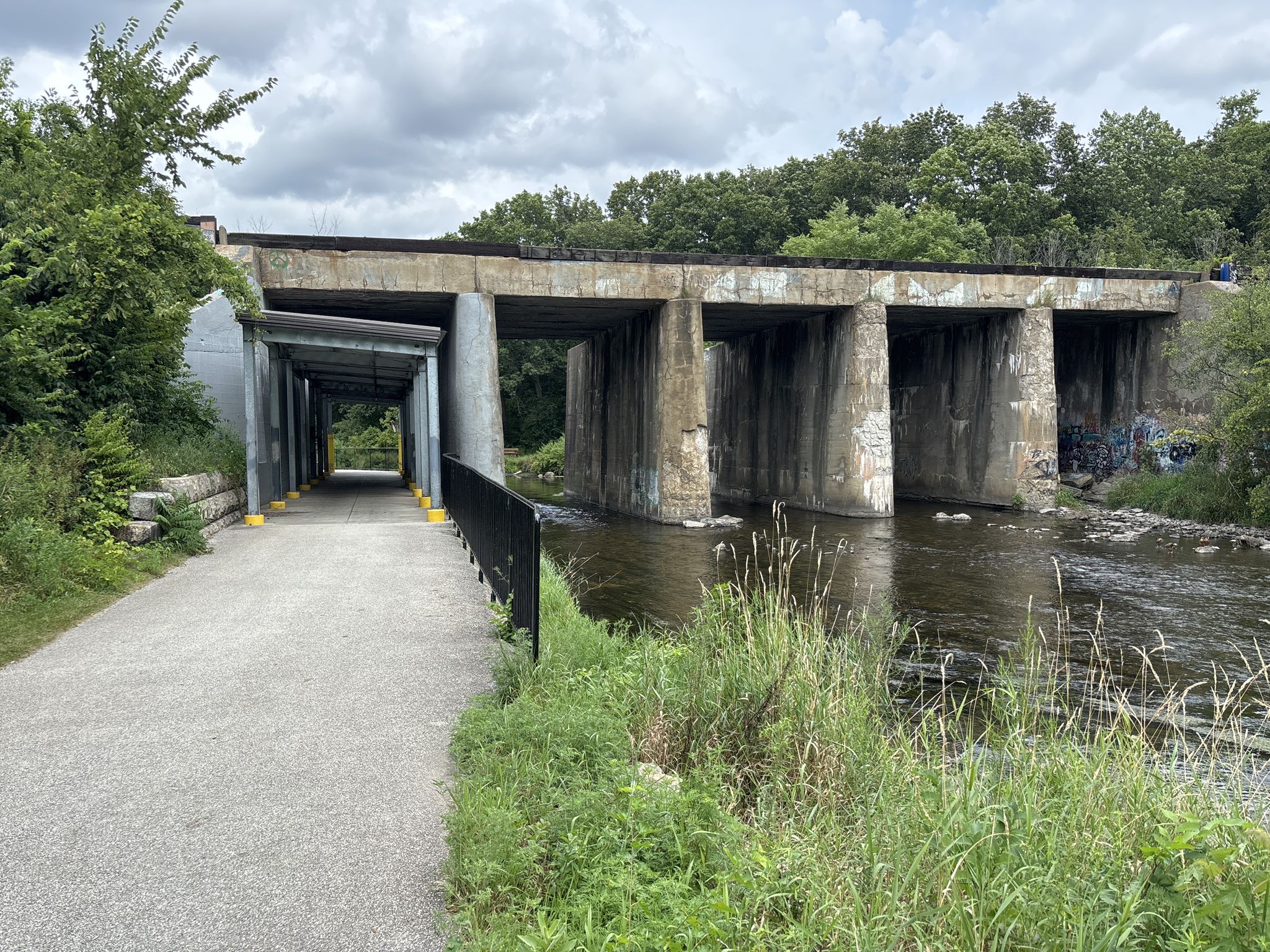 Concrete bridge over a river with a path and covered walkway. - West Branch DuPage River Trail Loop