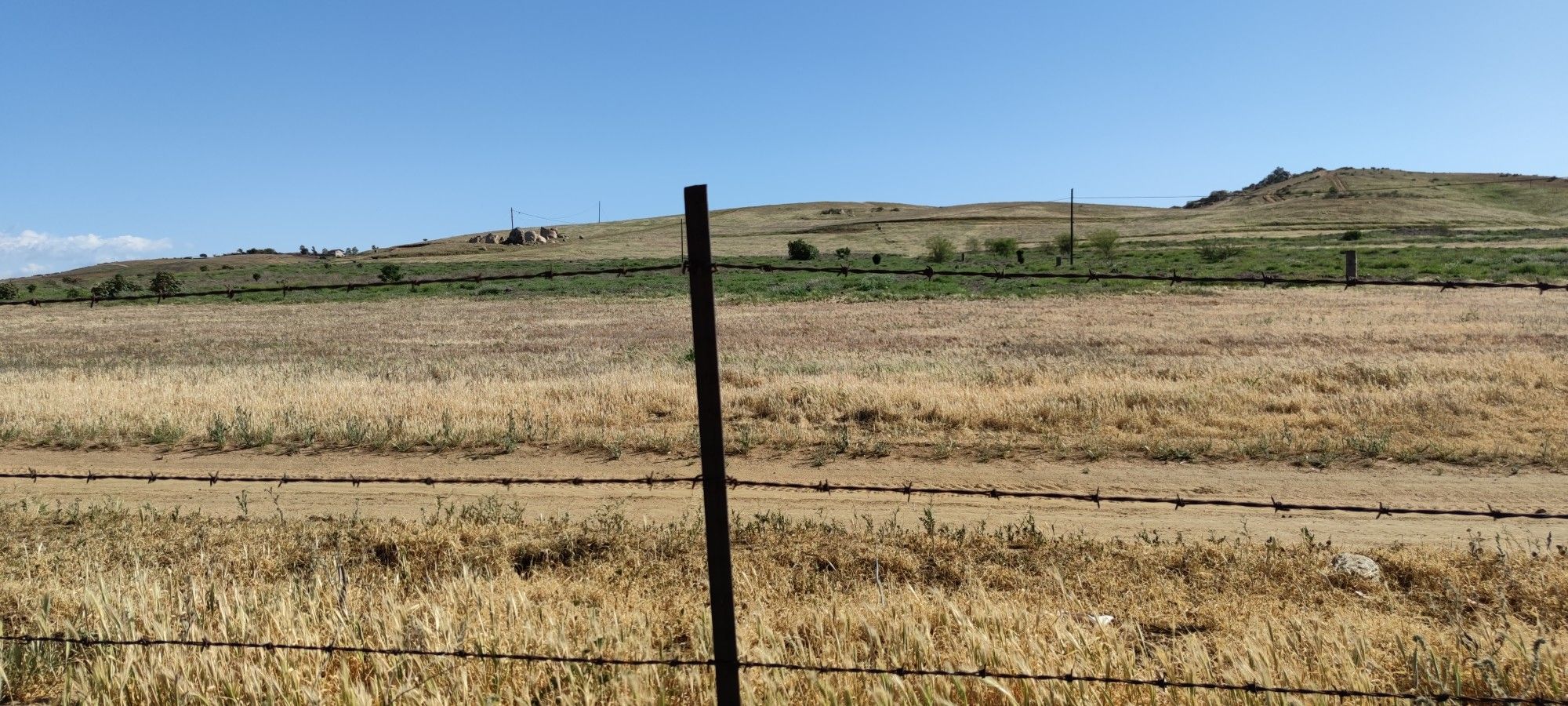 Barbed wire fence in front of a dry grassy field and rolling hills under a clear sky. - Hidden Valley Viewpoint – Santa Ana River Trail loop from Hidden Valley Wildlife Area
