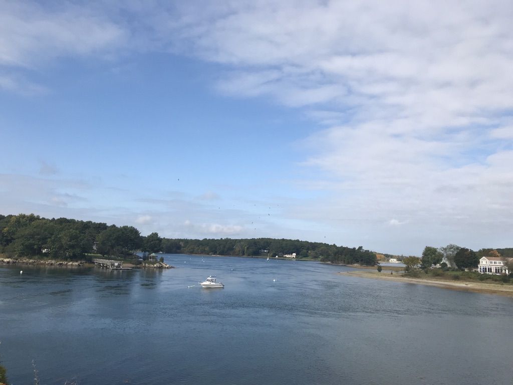 A wide river with a boat, forested banks, and a partly cloudy sky. - Wallis Sands Beach overlook – Odiorne Point loop from Rye