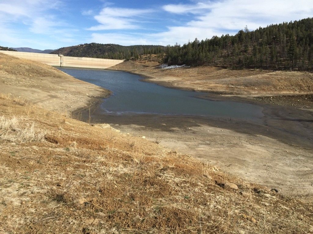 A low reservoir with exposed dry banks under a bright blue sky. - Grindstone Lake Trail Extended