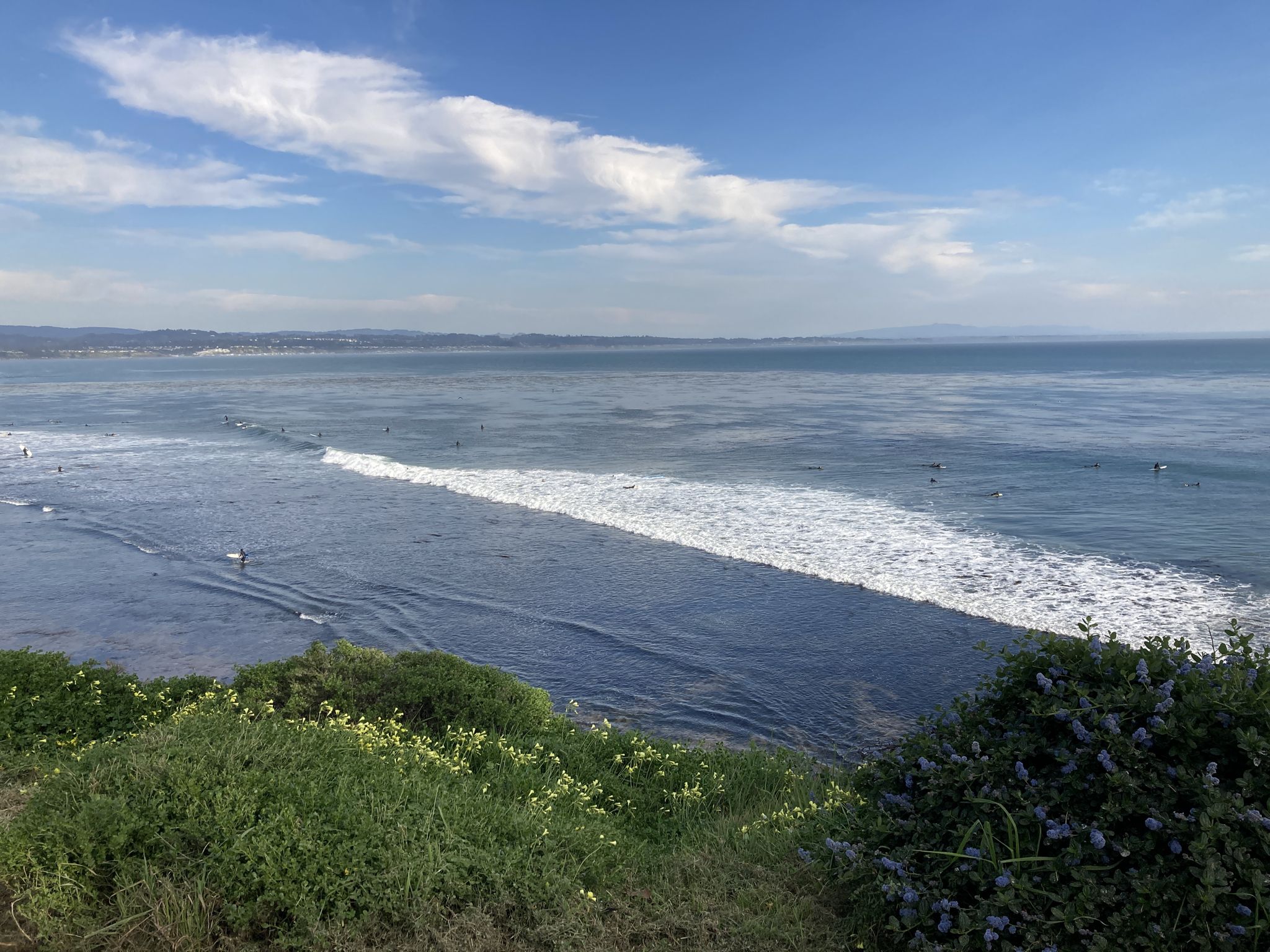 Wide ocean view with breaking waves and distant surfers under a clear sky. - Pleasure Point Beach – Moran Lake Beach and Park loop from Capitola