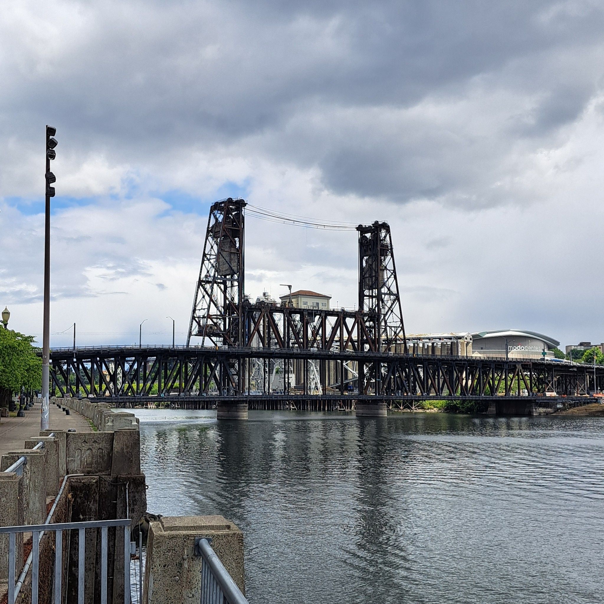 A large metal bridge spans a river under a dramatic cloudy sky. - Broadway Bridge – Leif Erikson Drive loop from PSU Urban Center/Southwest 6th & Montgomery