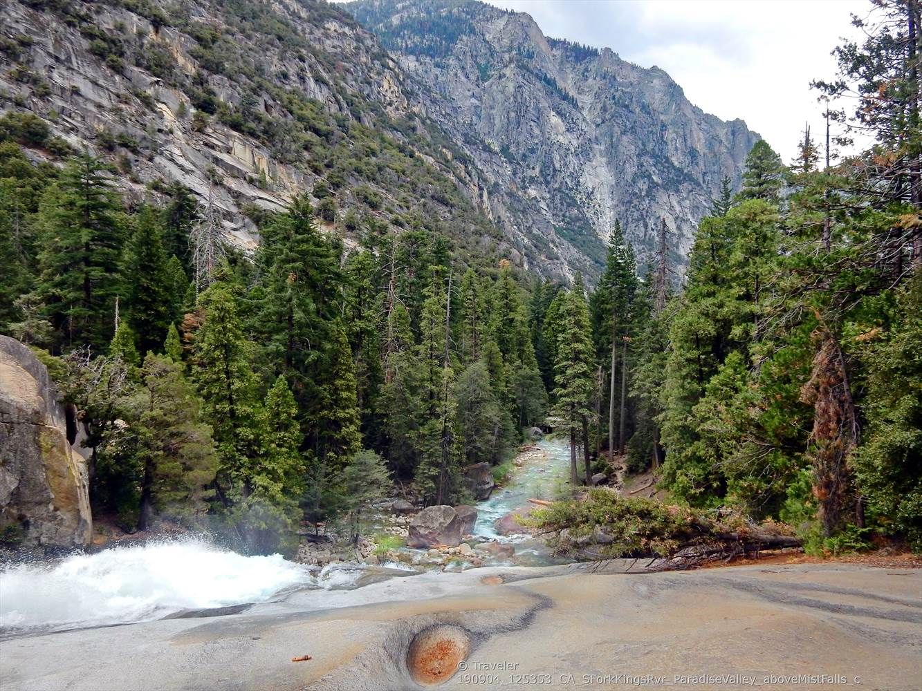 Rushing river flowing over rocks in a deep, forested canyon under cloudy skies. - Mist Falls
