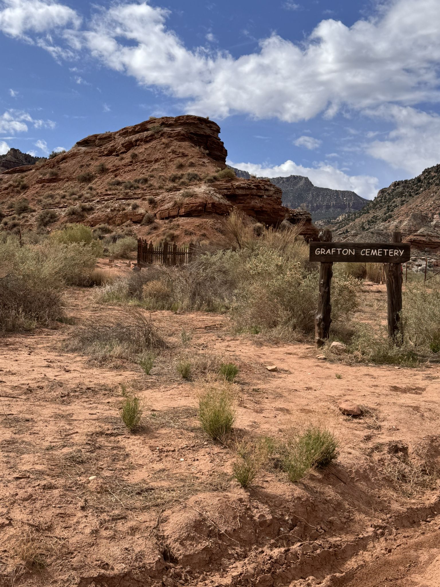 A wooden sign in a sunny, arid desert landscape with red rock hills. - Grafton Cemetery Viewpoint Trail