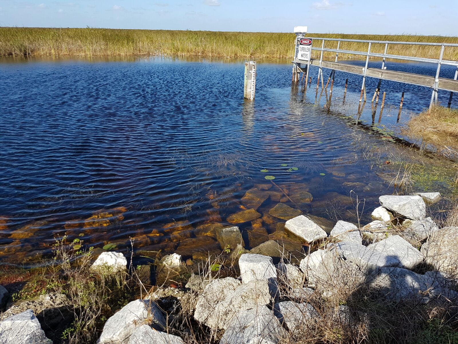 Clear water with rocks and a wooden pier under a sunny sky. - Everglades National Park – Markham Park loop from Riverside Park