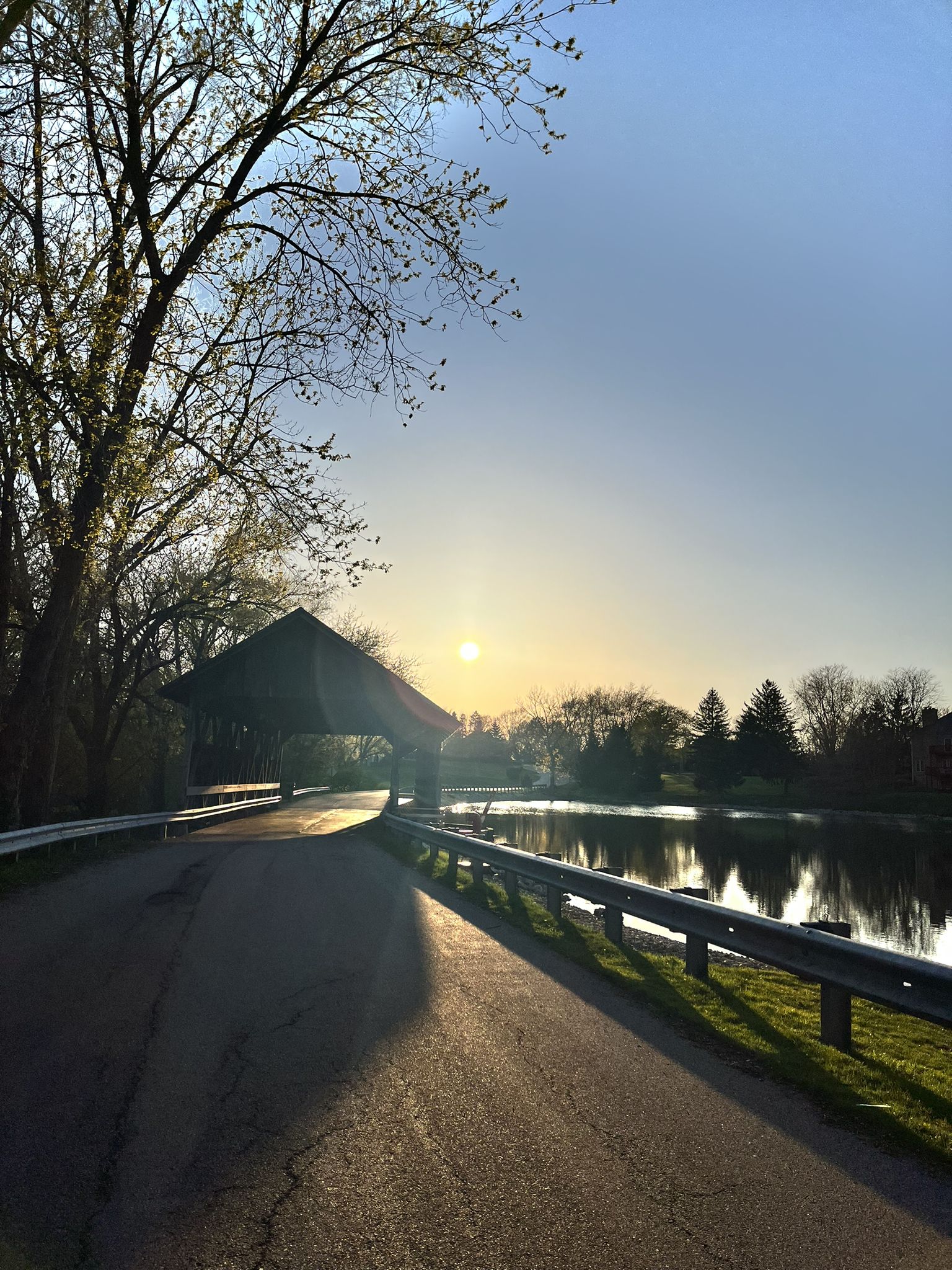 A covered bridge and road next to a lake at sunset. - Lake of the Coves loop via Covered Bridge Road