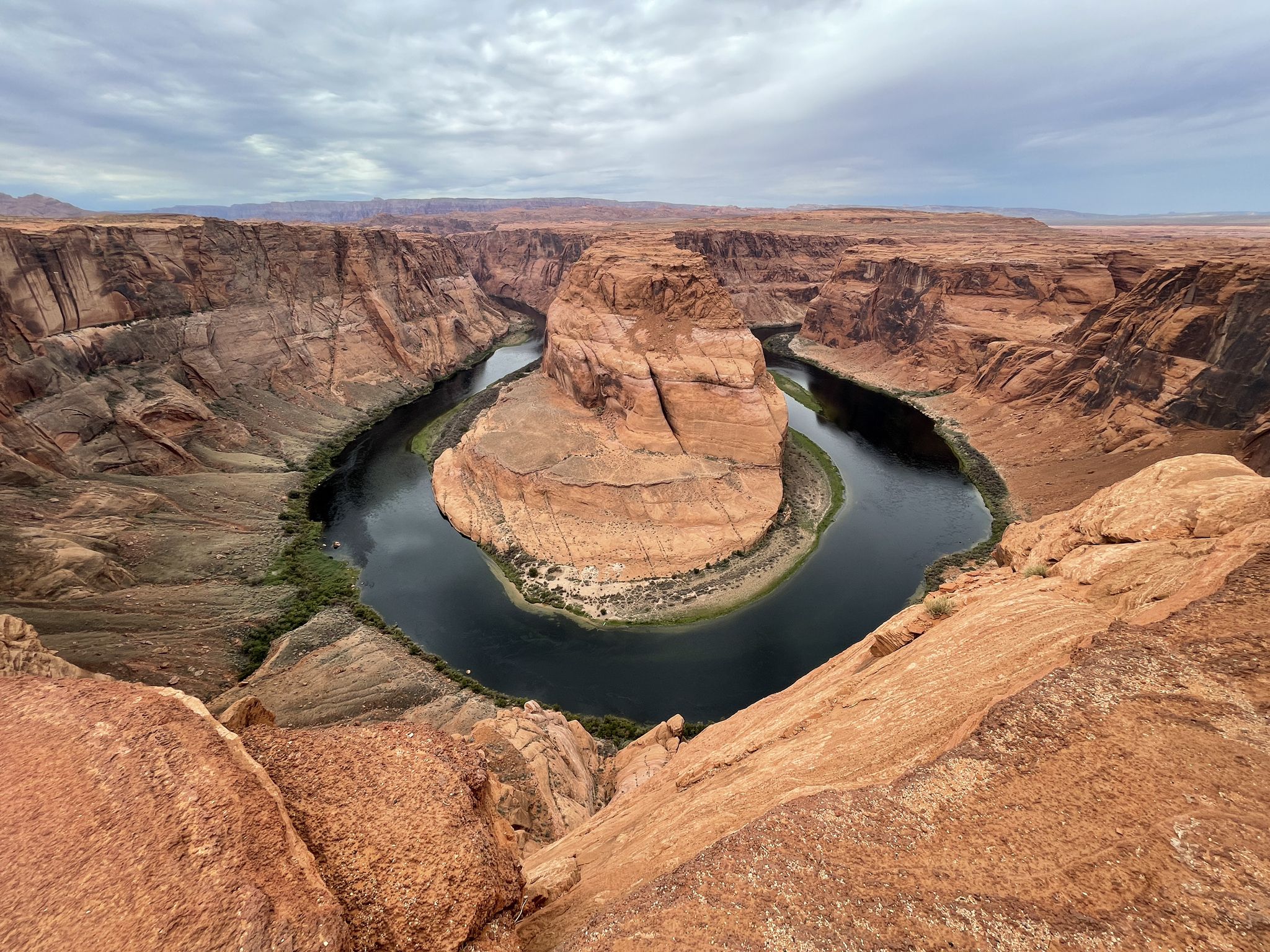 Overcast view of a horseshoe river bend surrounded by red rock cliffs. - Horseshoe Bend Trailhead – View of Horseshoe Bend loop from Horseshoe Bend