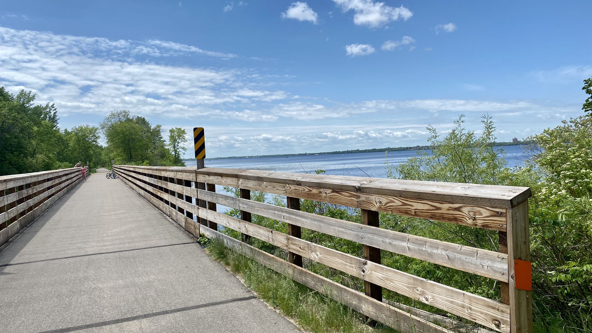 Long wooden boardwalk over water, with a calm lake and blue sky. - South Shore Beach loop from Lavinia