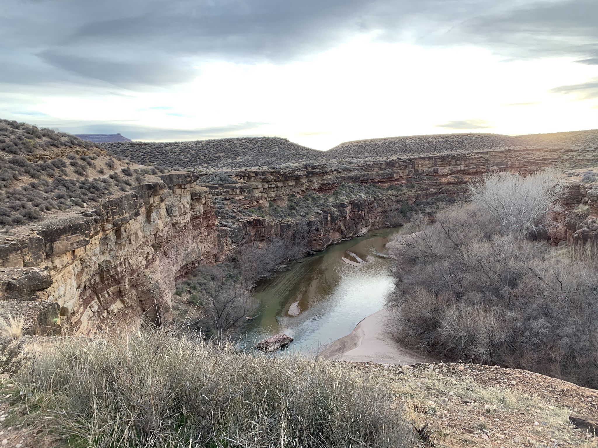 River winding through a desert canyon under an overcast sky. - JEM Trails – MTB Trails in Hurricane, Utah