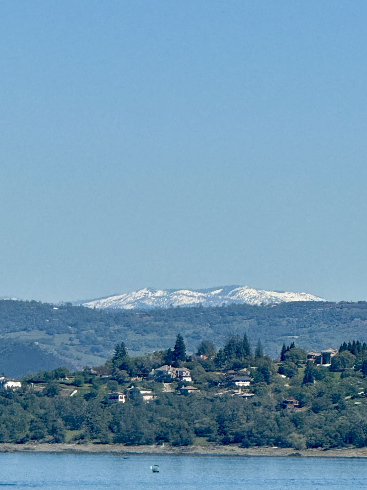 Distant snow-capped mountains rise above hills and a calm lake. - Folsom Dam – Folsom Lake loop from Roseville