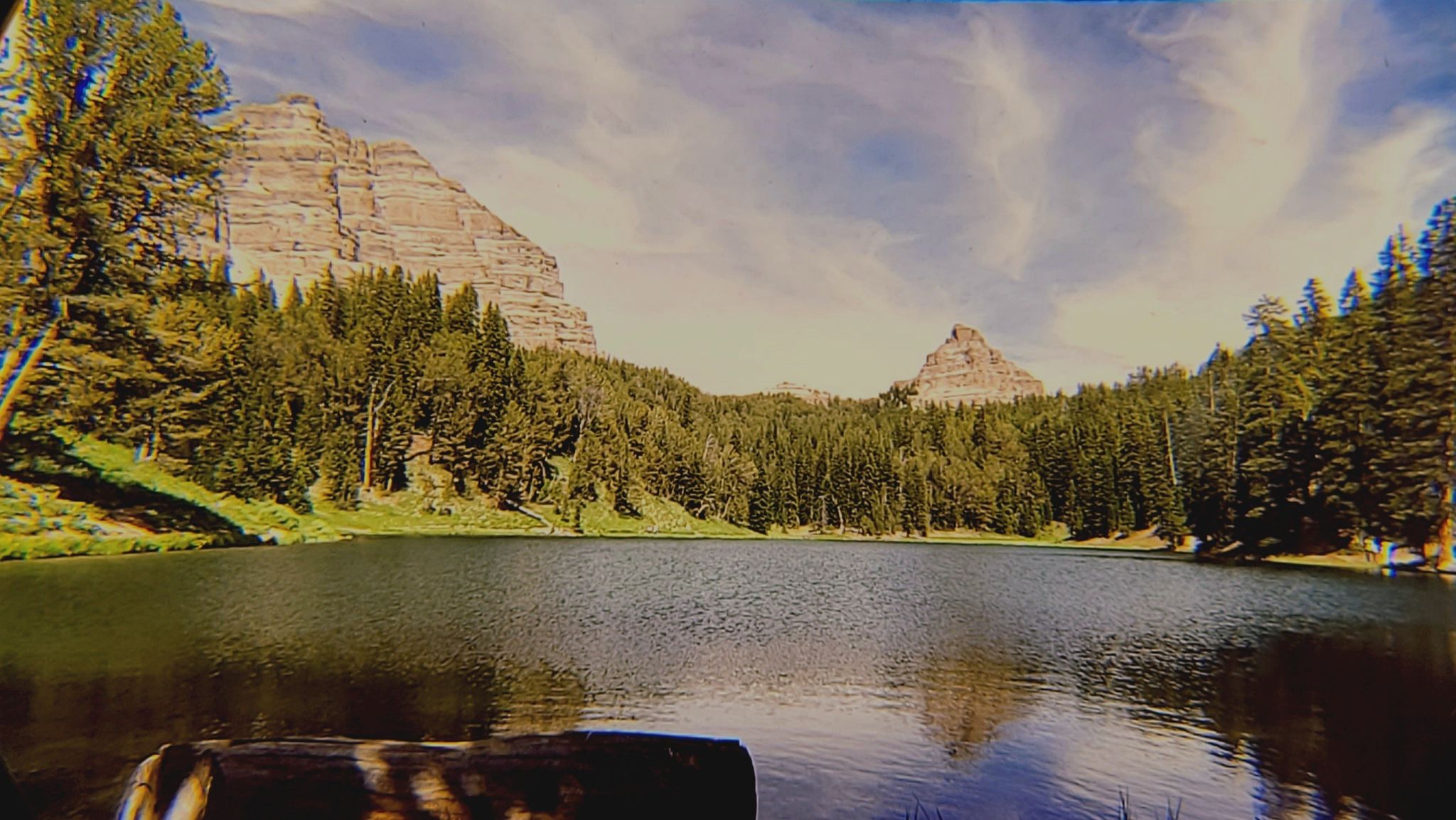 A serene mountain lake surrounded by dense forest and rocky peaks under clouds. - Pueblo to Beulah loop