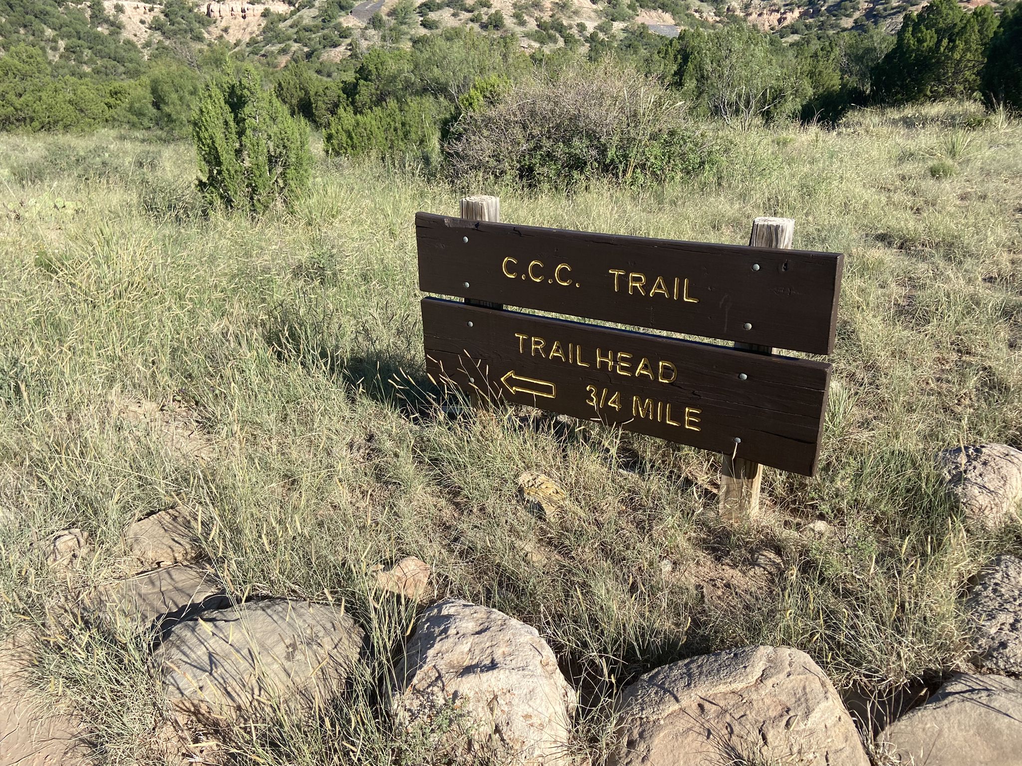 Wooden trail sign in tall grass indicating a trailhead 3/4 mile away. - CCC Trail