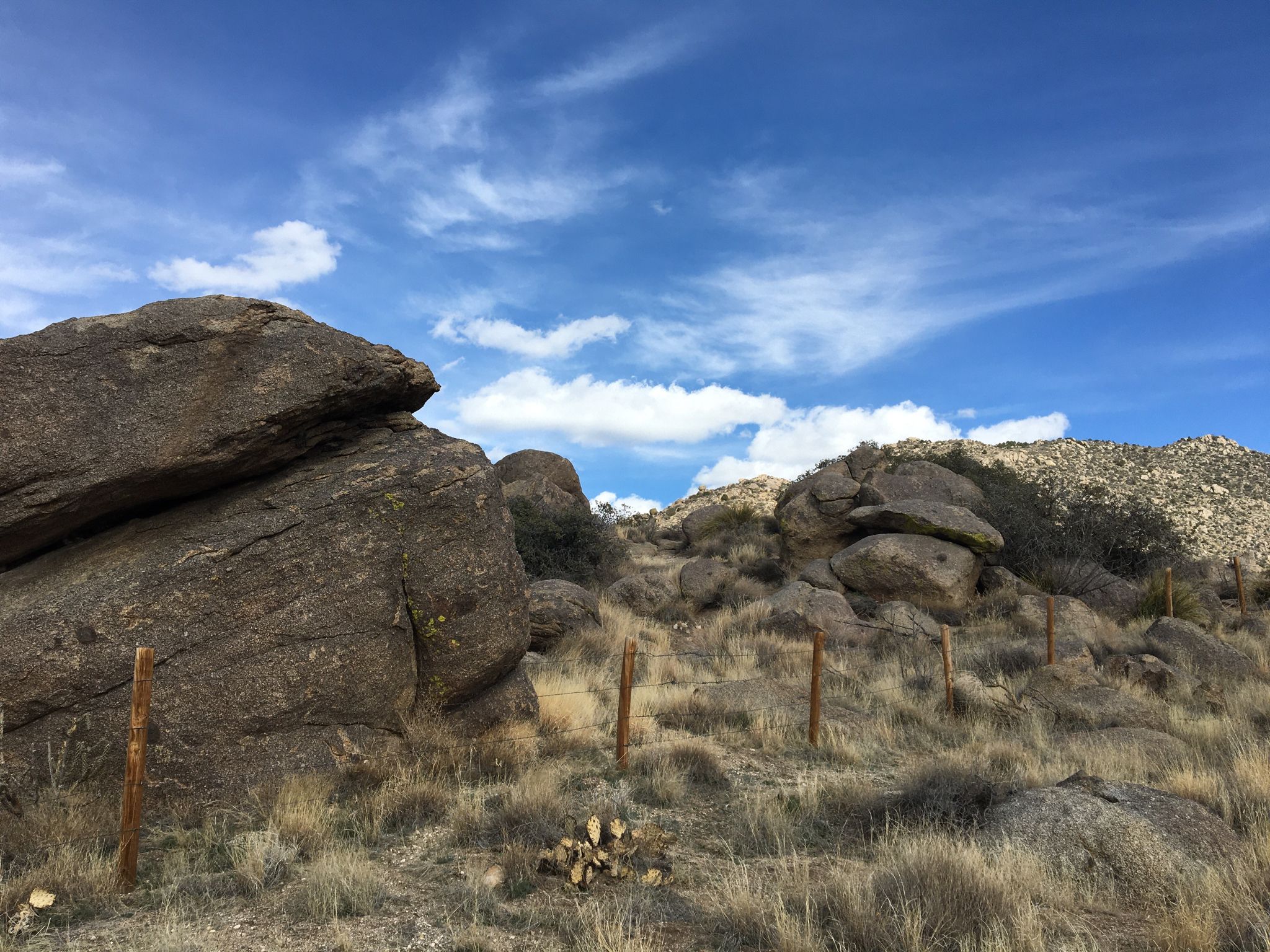 Large boulders and dry grass on a rocky hillside under a bright blue sky. - Juan Tabo Cabin Ruins – Balloon Fiesta Park loop from Los Ranchos/Journal Center