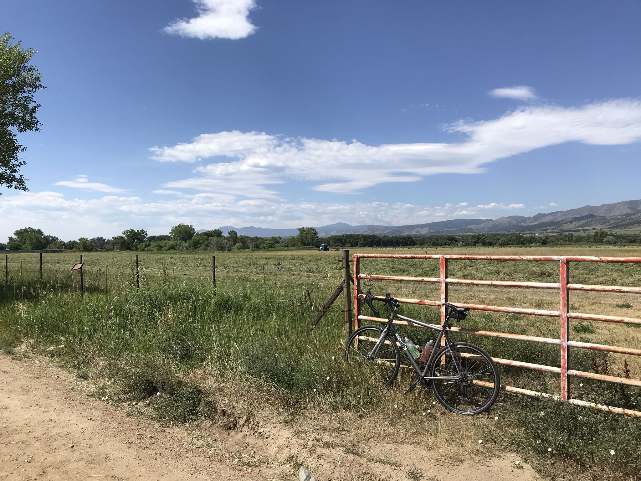 Bicycle leaning on a rusty fence beside a dirt road and green field. - McIntosh Lake – Nelson Loop loop from McIntosh Lake