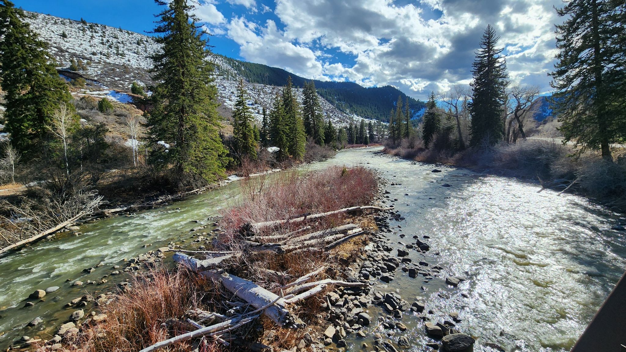 A rocky river flows through a snowy mountain valley with pine trees. - Eagle – Eagle Valley Trail loop from Bocco Mountain
