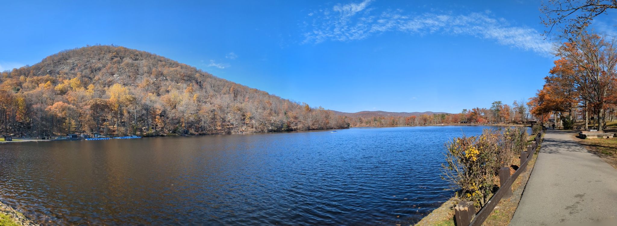 Panoramic view of a calm lake beside a forested hill under a clear blue sky. - Perkins Memorial Tower – Hessian Lake loop from Fort Montgomery