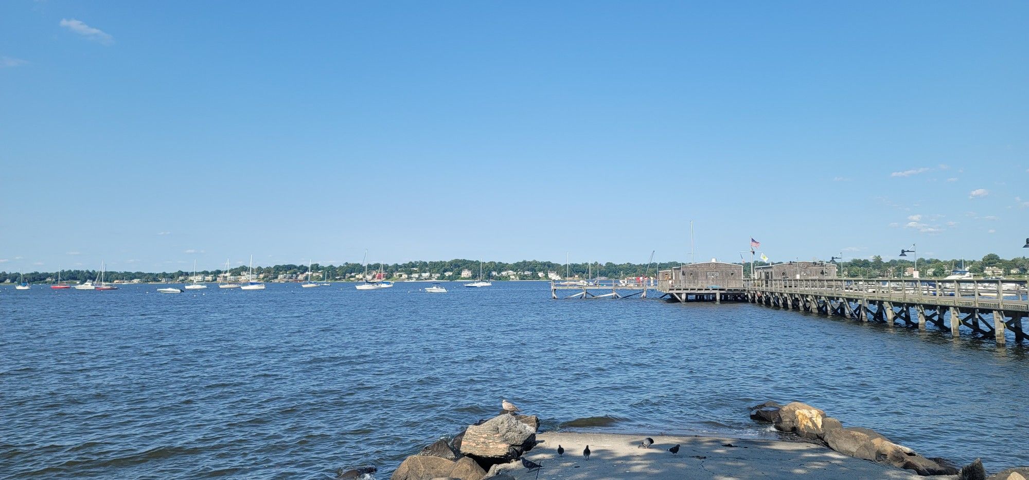 Wide water body with many boats and a long wooden pier. - Manorhaven to Valley Stream via Commack