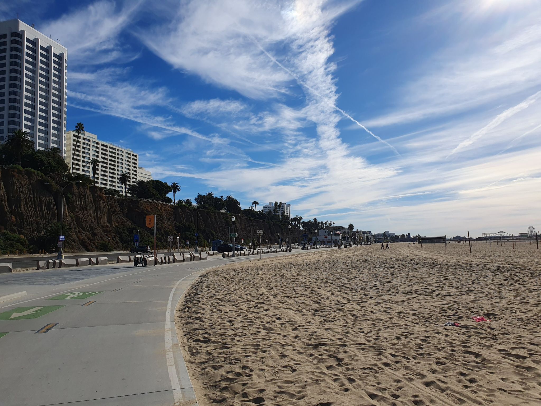 Sunny beach with a paved path, tall buildings, and distant ocean. - Santa Monica Pier – Will Rogers State Beach loop from Ballona Wetlands Ecological Reserve