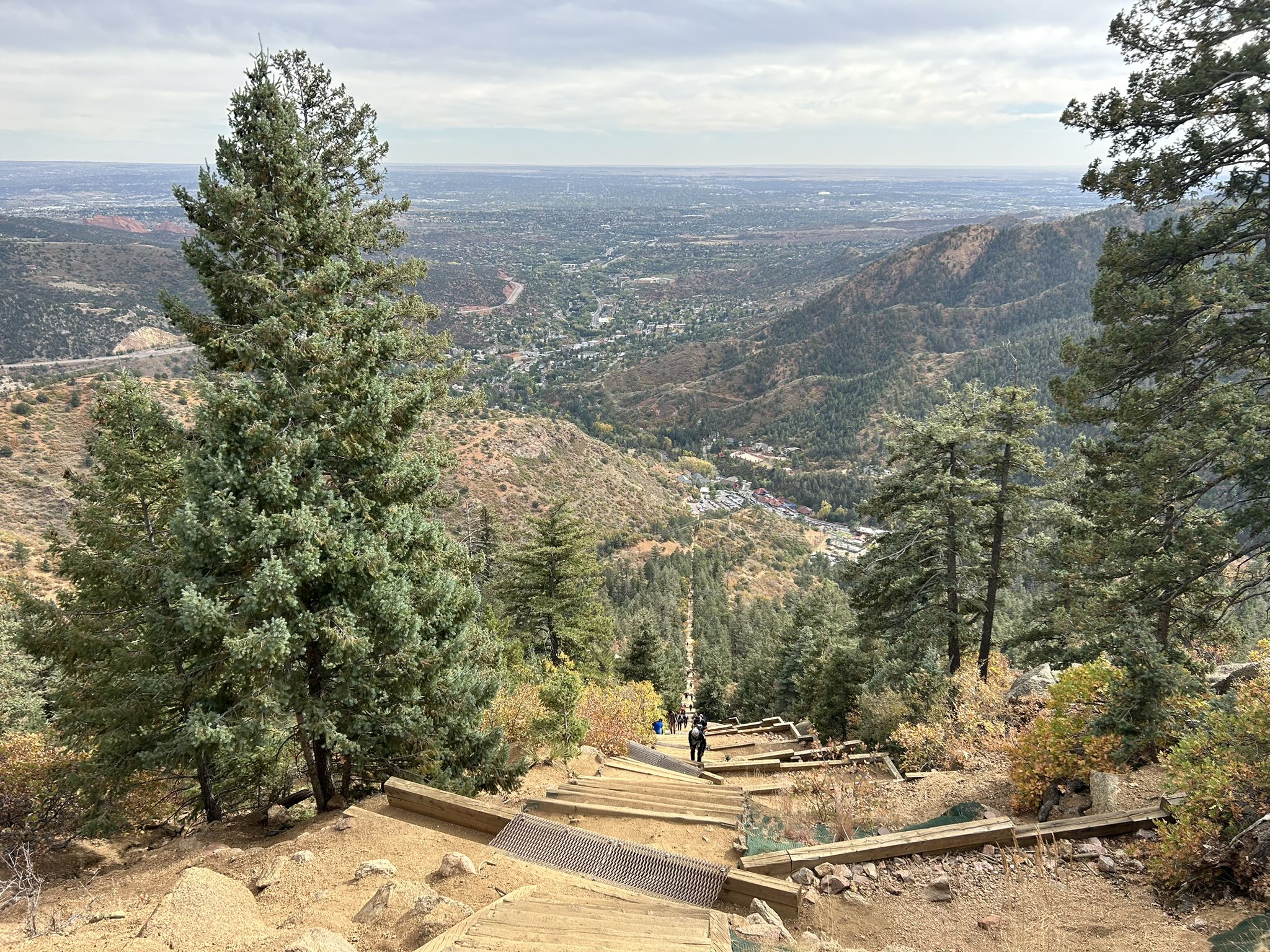 Steep wooden stairs descending a mountain, overlooking a valley. Overcast sky. - Manitou Incline and Barr Trail Loop