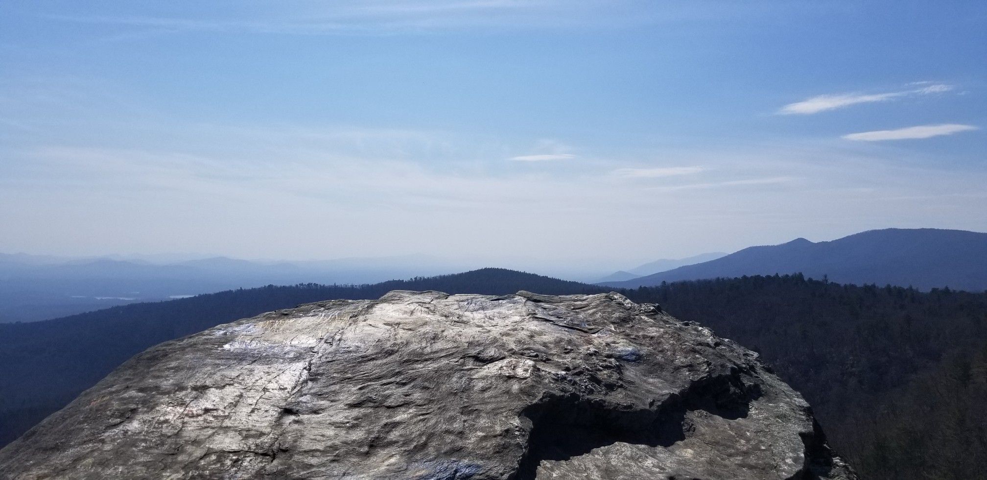 A large rock overlooks distant mountains and valleys under a clear blue sky. - Linville Gorge Trail & Pinch In Trail loop