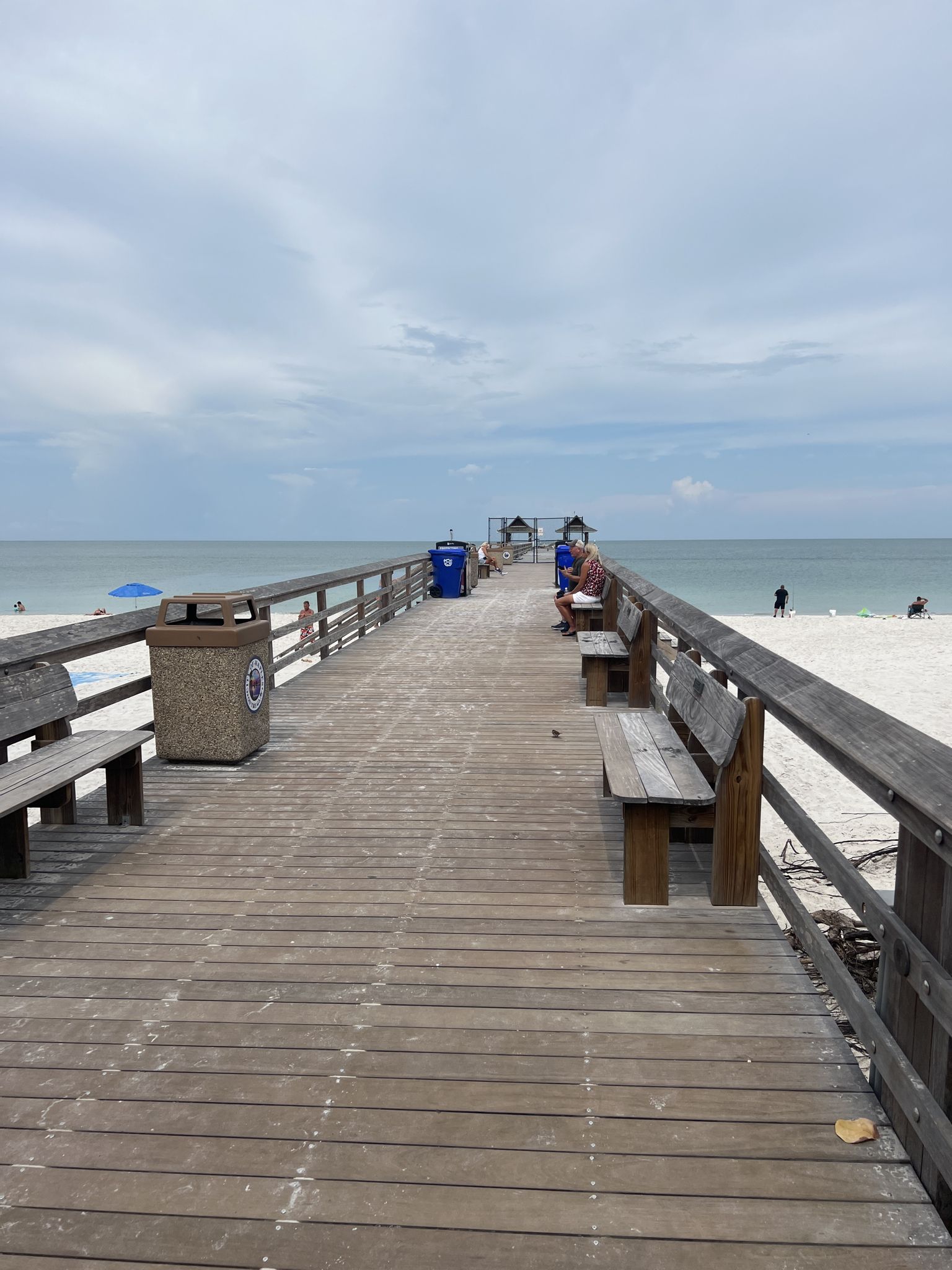 A long wooden pier with benches extends over the ocean. - Naples Pier and Beach – Naples Pier loop from The Naples Preserve