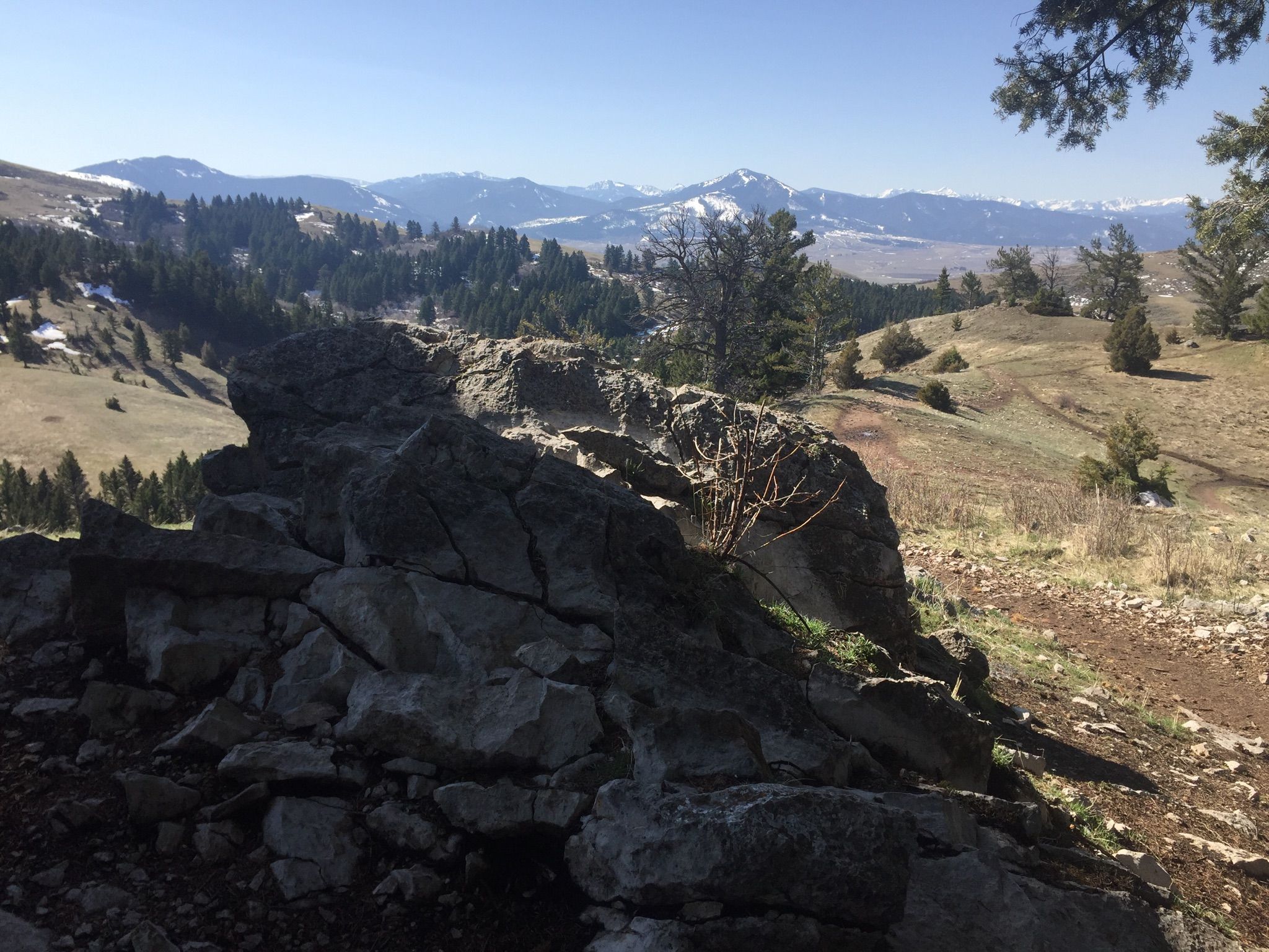 Large rock formation on a sunny hillside with distant mountains and trees. - Drinking Horse Mountain Trail