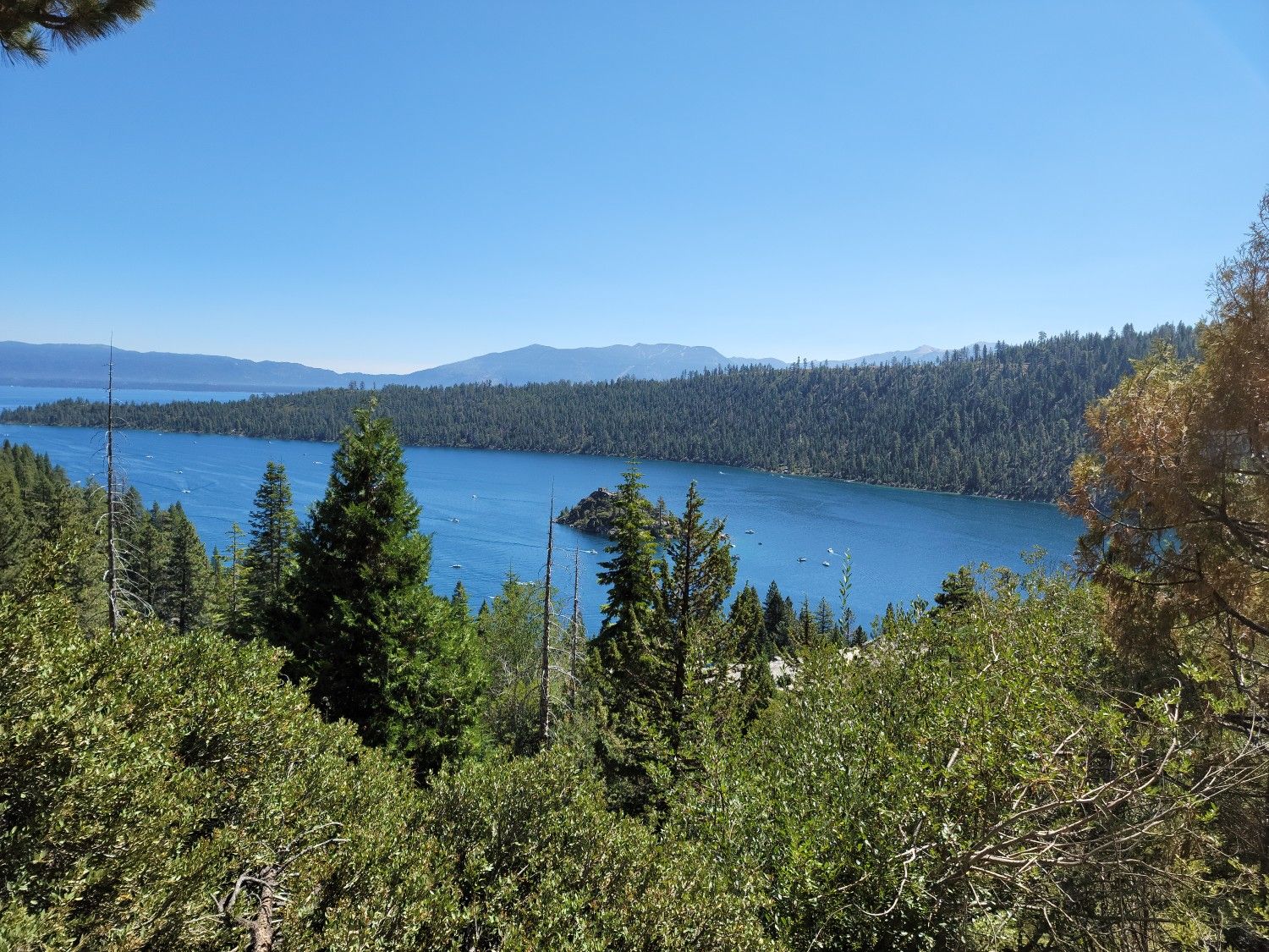 Overlook of a blue lake with a small island, surrounded by green trees and mountains. - Emerald Bay Road to Vikingsholm Trail loop