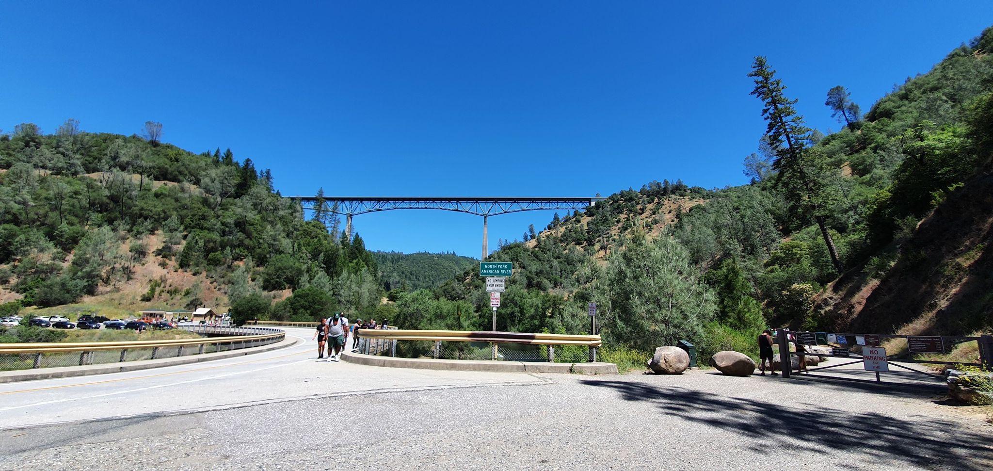 People stand near a road and large bridge over a forested river valley. - Confluence and Clementine Trail Loop