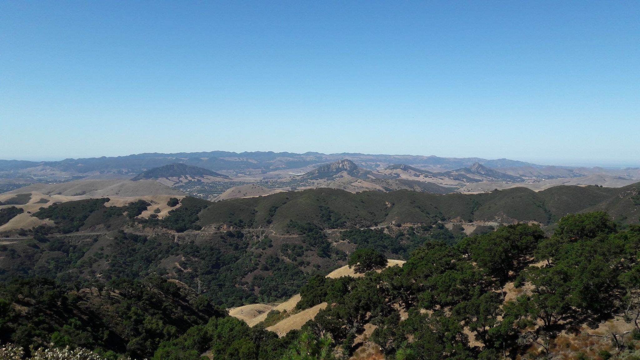 Vast mountain landscape with green trees and dry hills under a bright blue sky. - Mount Lowe Road
