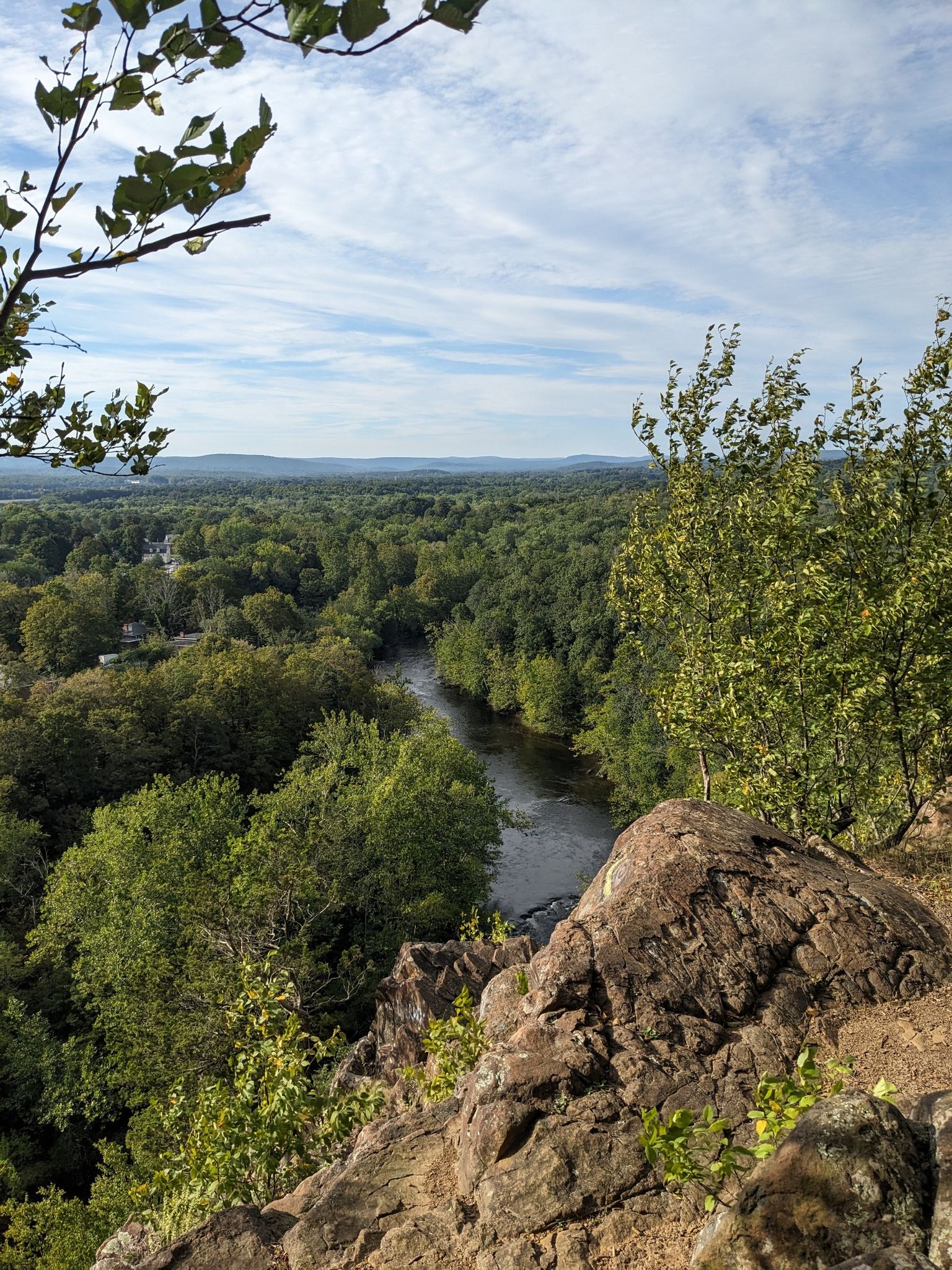 Panoramic view from a rocky cliff overlooking a river winding through a green forest. - Metacomet Trail to Tariffville Gorge