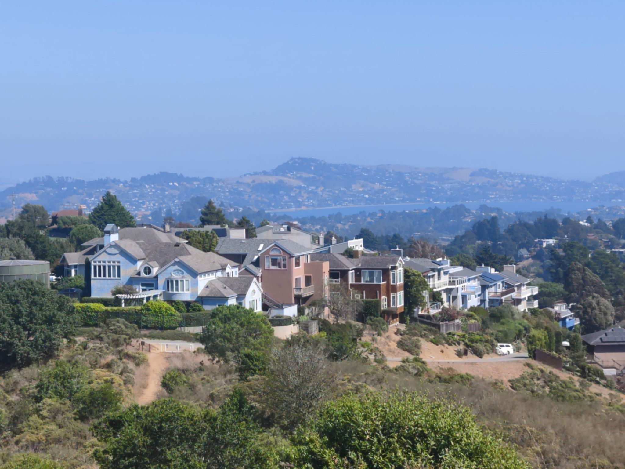 Houses on a sunny hillside overlooking distant hills and water. - Homestead Valley Big Loop
