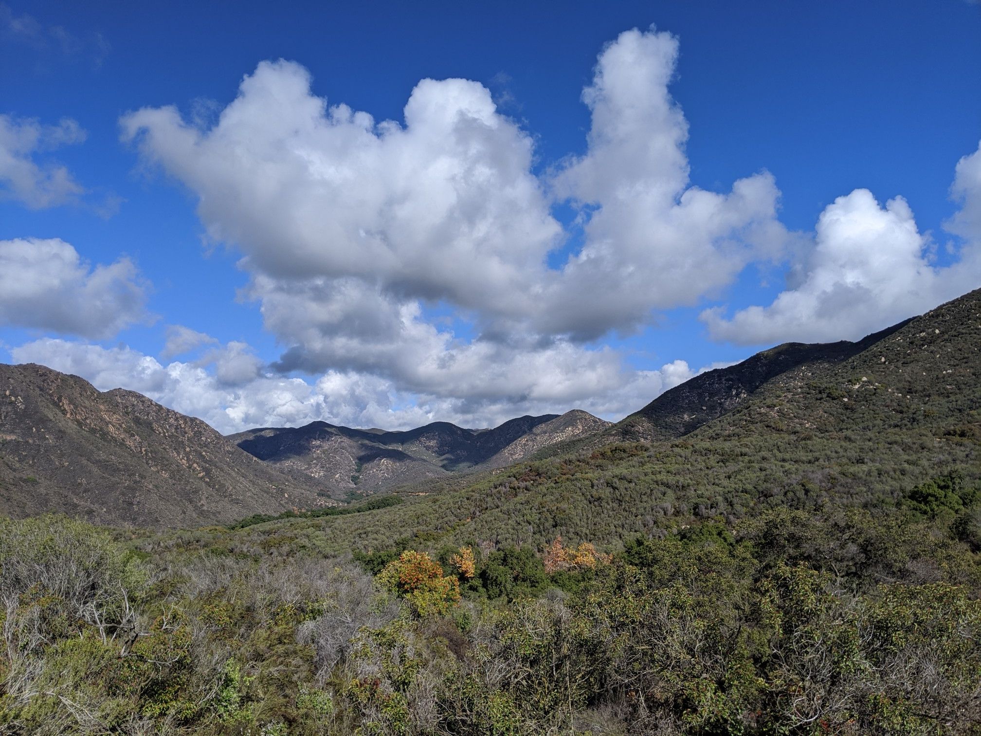 Sunny mountain valley with green hills, distant peaks, and white clouds. - Fisherman's Camp, San Mateo and Tenaja Falls Loop Trail
