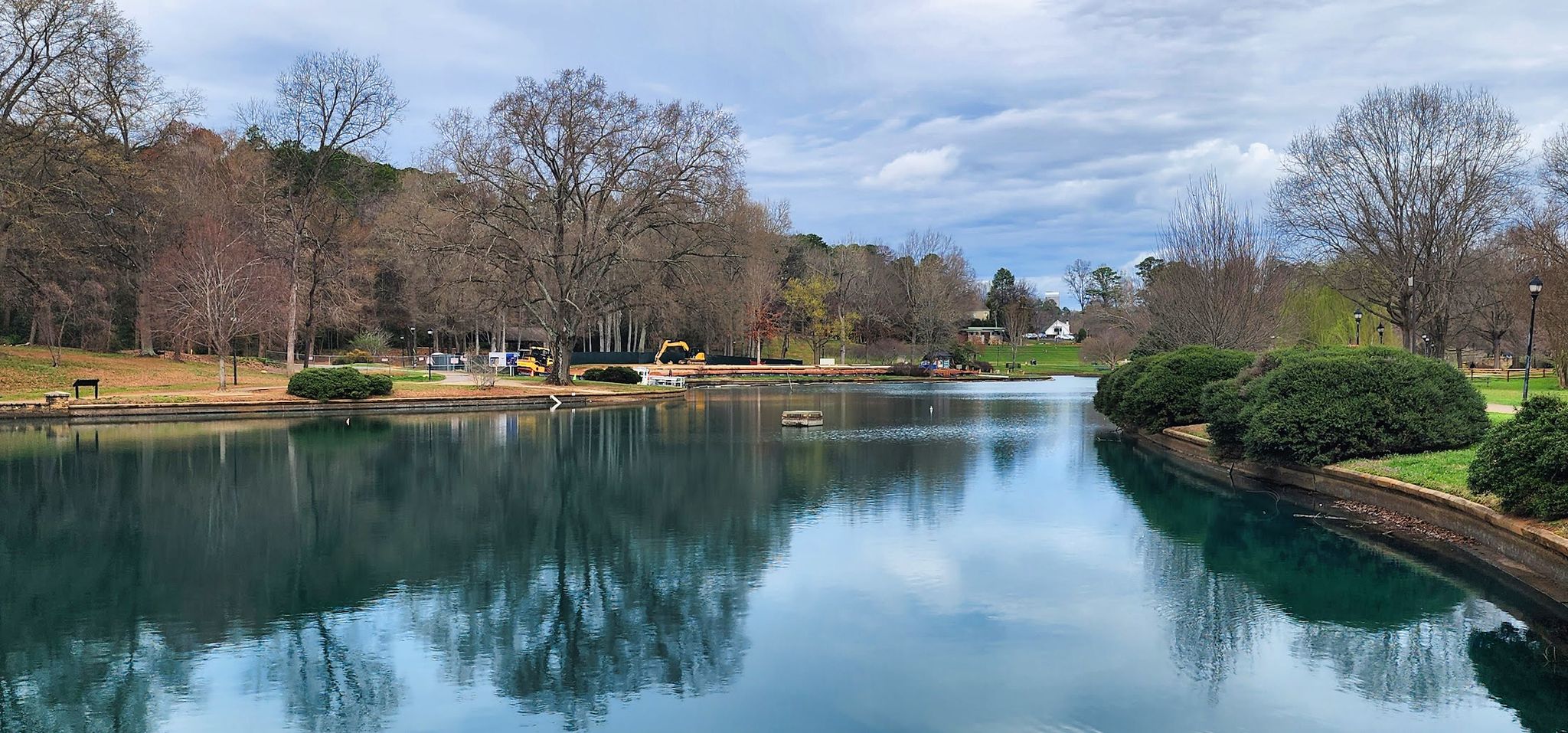 A calm lake reflecting bare trees under a cloudy sky. - Freedom Park Pond Loop