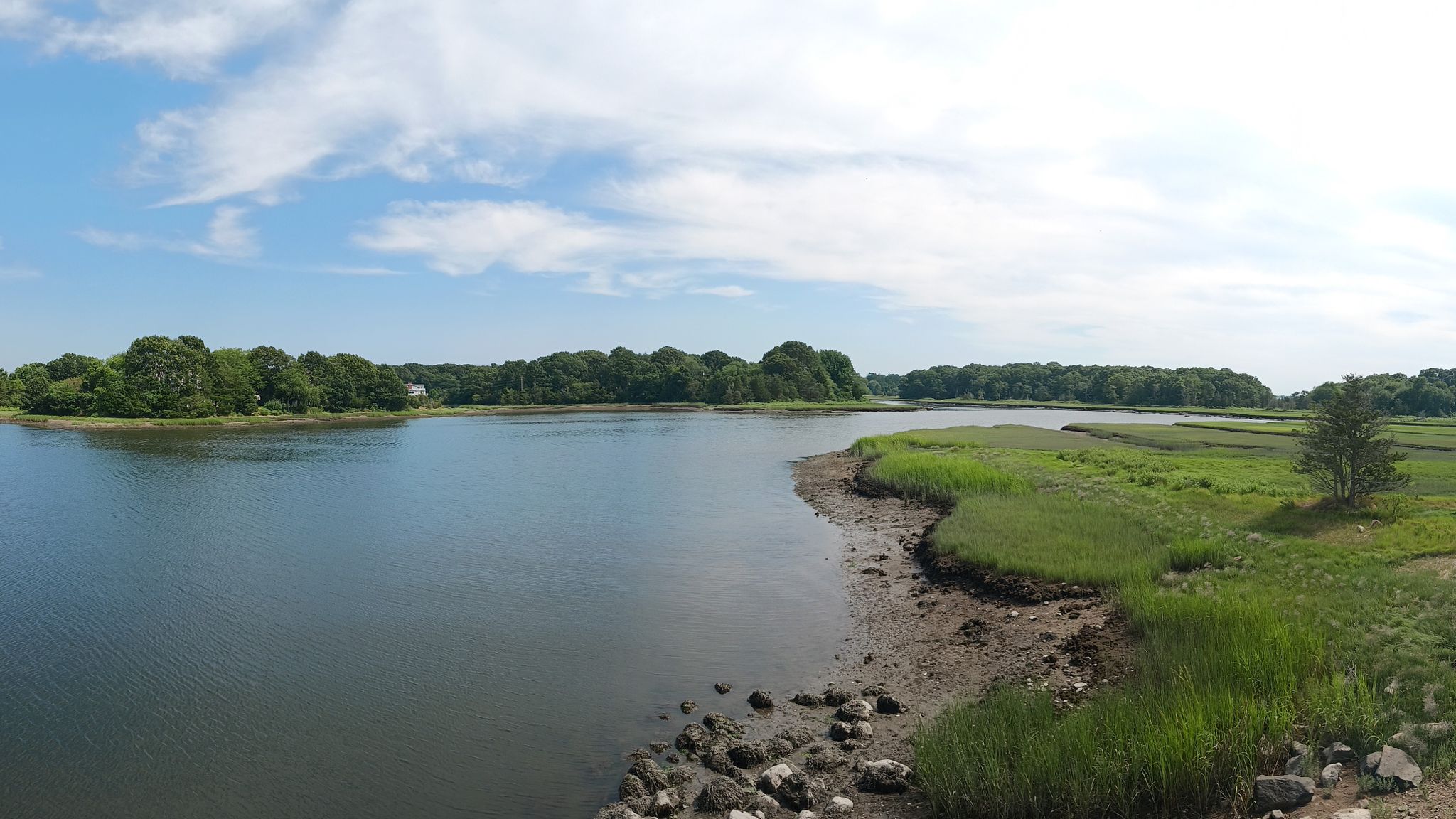 Wide river with green marshland and trees on banks under a partly cloudy blue sky. - Apponagansett Park and Beach – Apponagansett Beach loop from Dartmouth High School