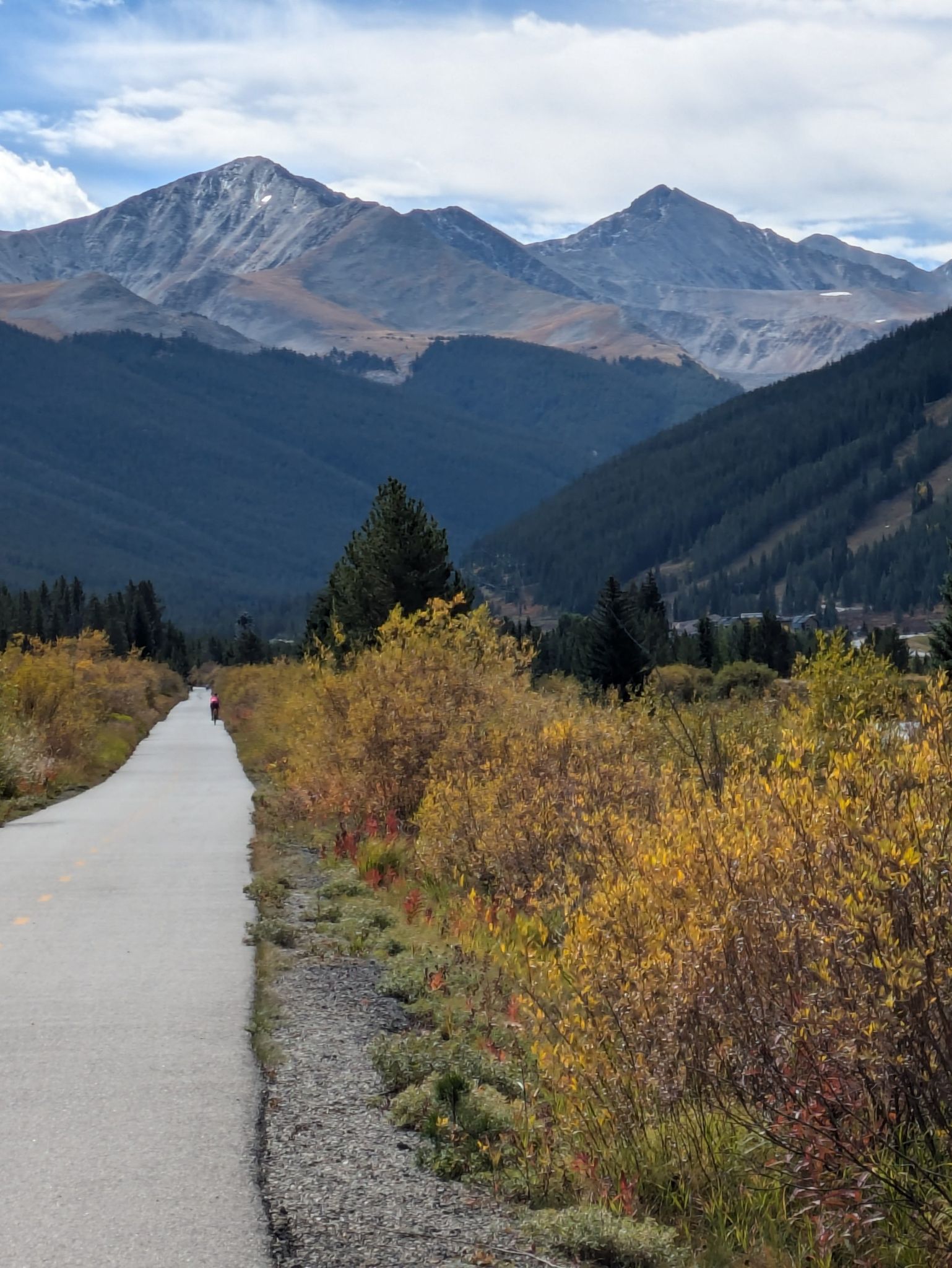 Paved road lined with autumn foliage leading to majestic distant mountains. - Tenmile Recpath