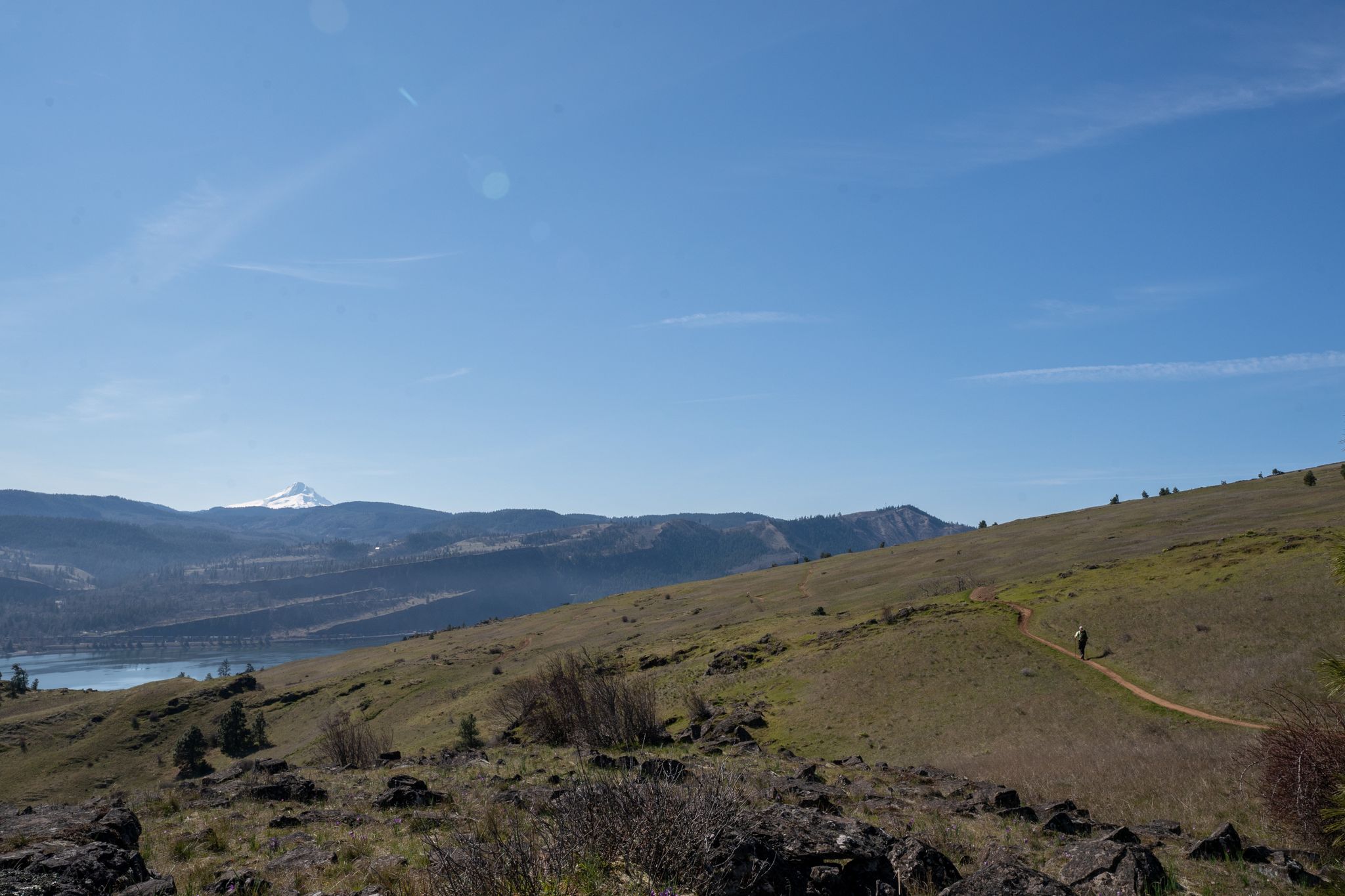 Two hikers on a trail across grassy hills with a distant snow-capped mountain. - Columbia River Gorge Scenic Byway: Washington