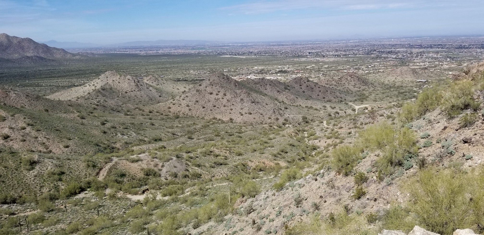 Panoramic view of desert hills overlooking a distant city under clear sky. - Goldmine Peak Viewpoint loop from Goldmine Trailhead