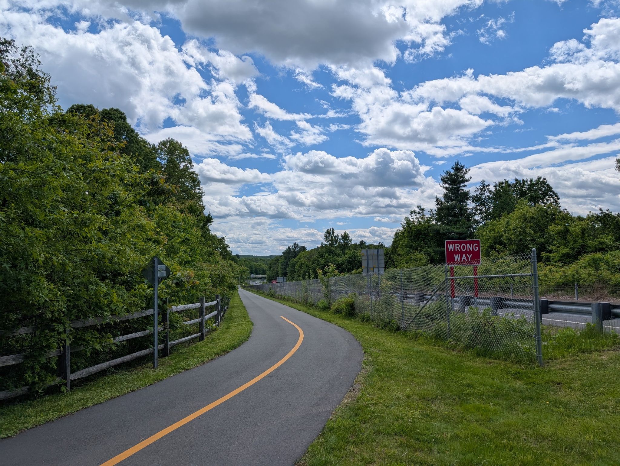 A winding paved path next to a "Wrong Way" sign under a cloudy sky. - Gay City State Park – Upper Case Pond loop from East Glastonbury Fish & Game Association