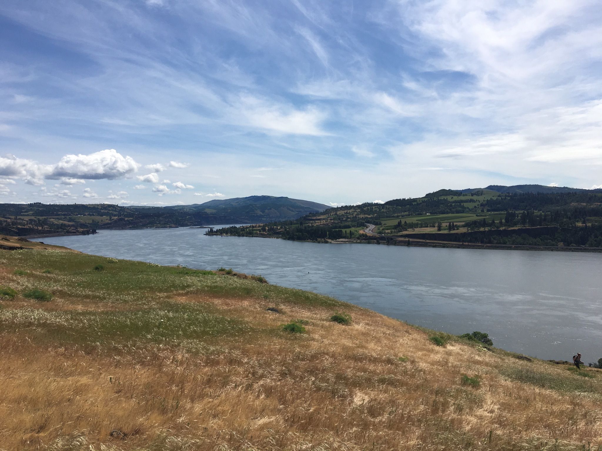 Wide river flows through rolling hills with green and golden grasses under blue sky. - Old Ranch Road and Little Maui Trail Loop