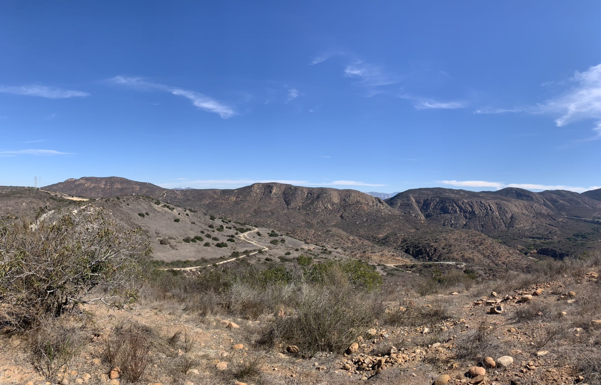 Rolling hills and valleys under a clear blue sky, with a winding dirt road. - Rim Trail loop from West Fortuna Staging Area