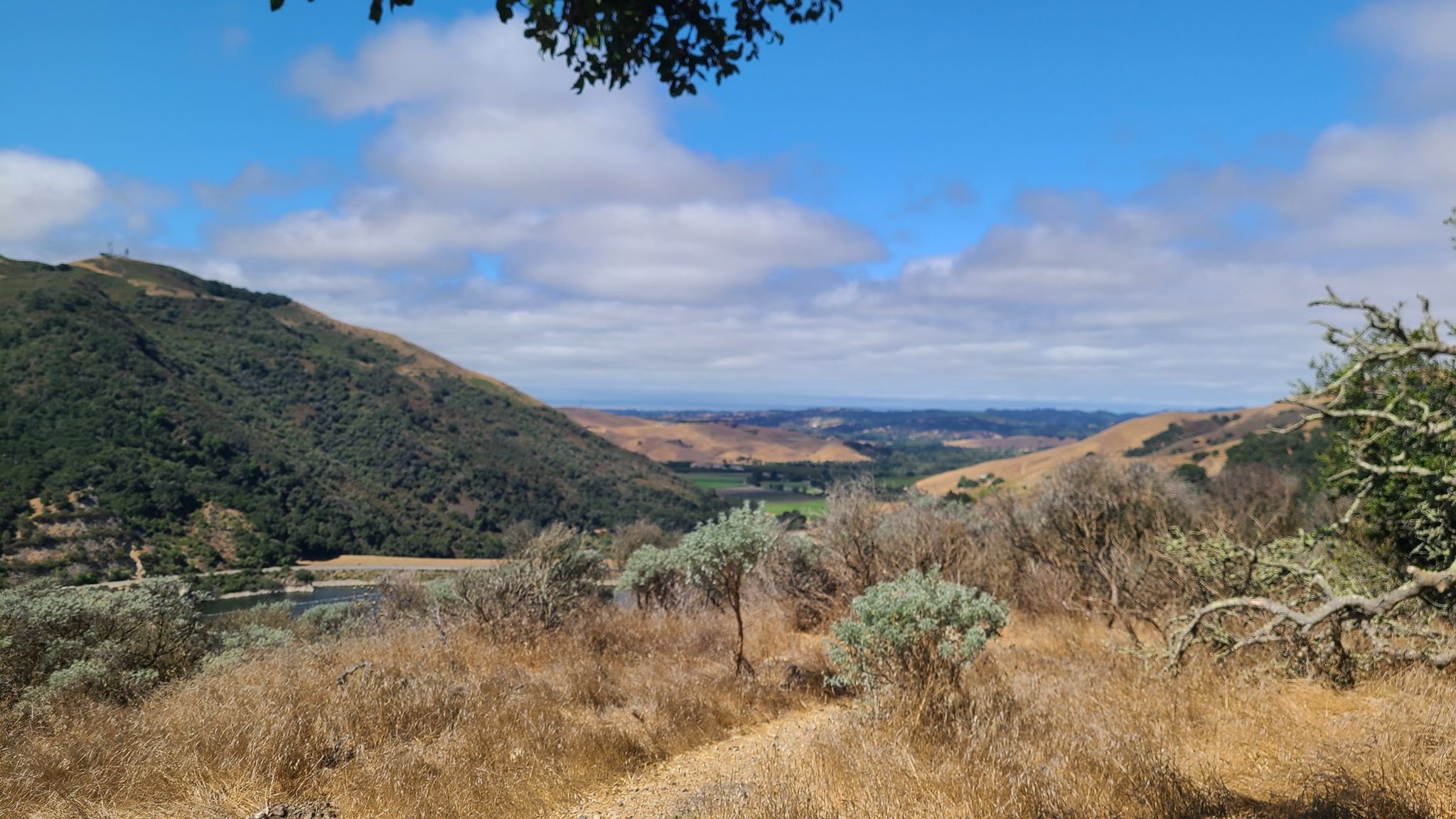 Dirt path through dry grass, overlooking a valley and distant lake. - Lopez Lake Recreation Area loop