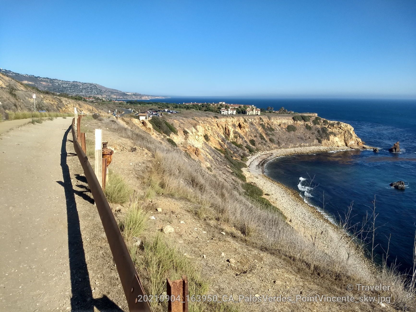 Sunny paved path along steep rocky cliffs overlooking the blue ocean. - Miramar Park – Torrance Beach loop from Palos Verdes