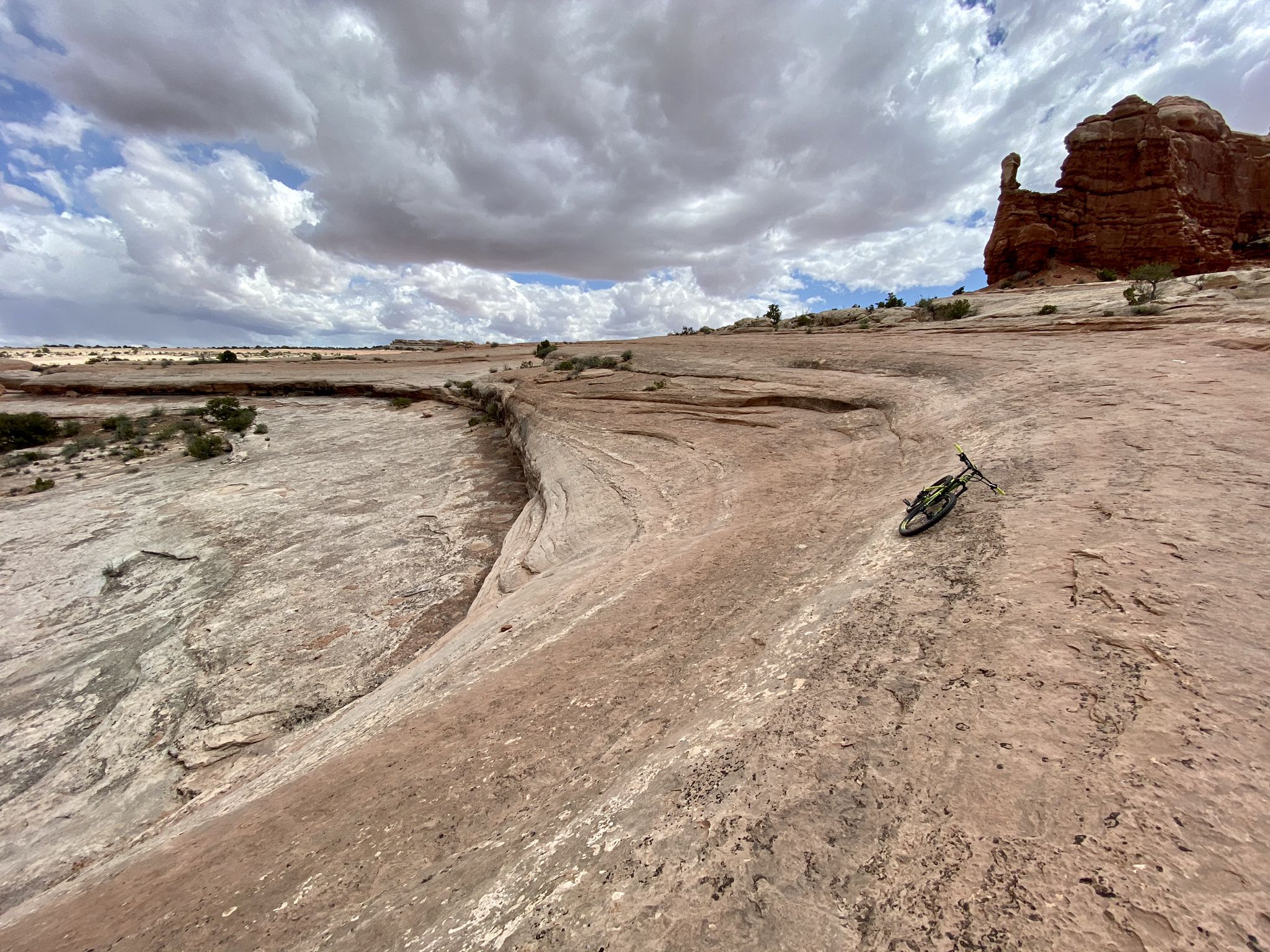 Mountain bike resting on a rocky desert slope under a cloudy sky. - Lower Monitor & Merrimac Trail Loop