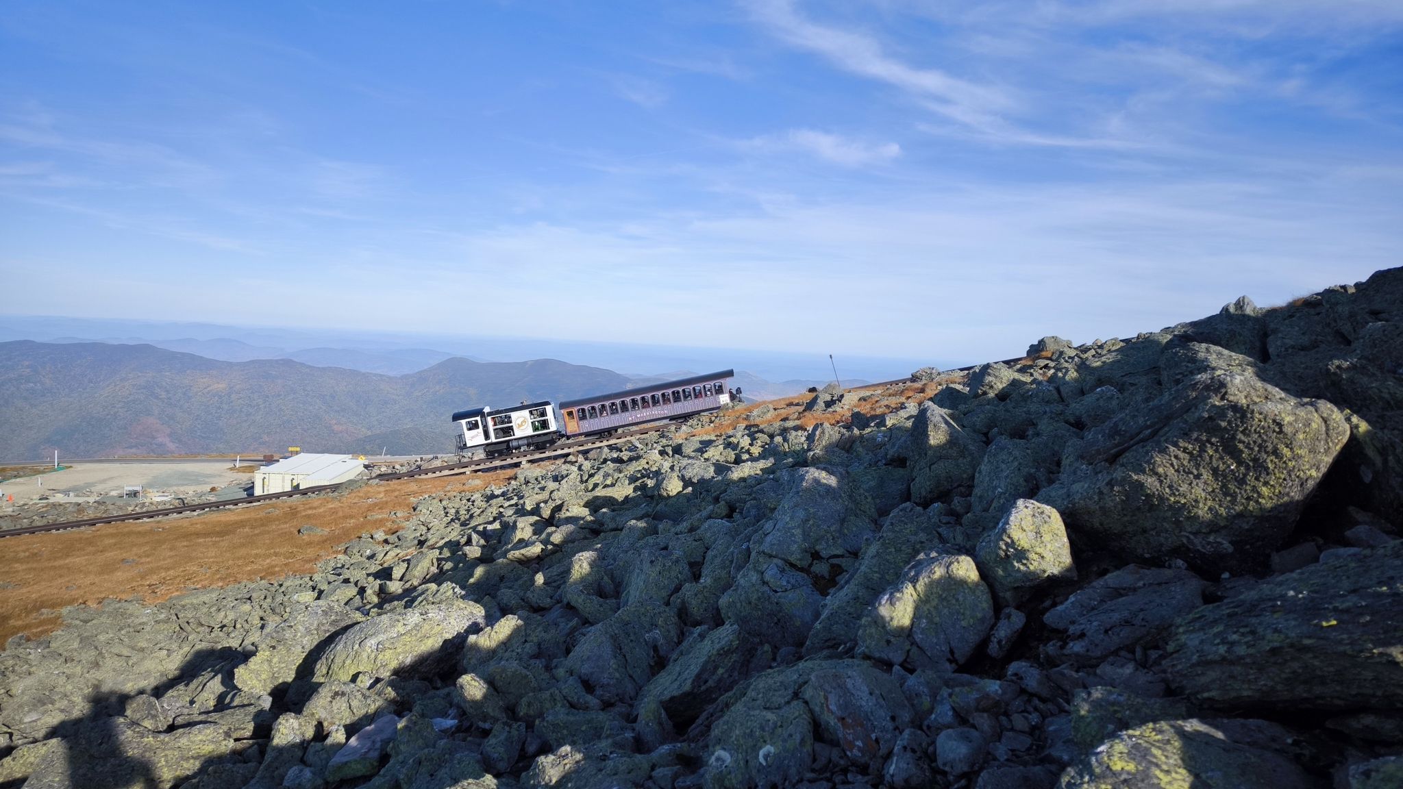 Train car on a rocky mountain slope under a clear blue sky. - Mount Washington via Huntington Ravine and Lion Head Trail