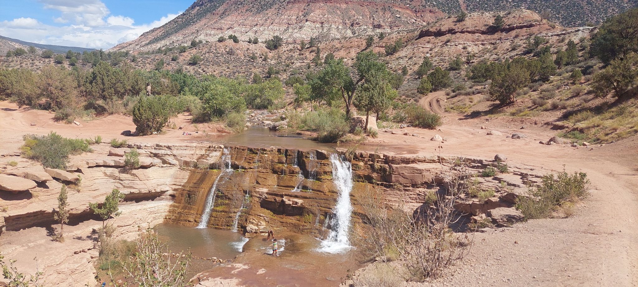 Multiple small waterfalls cascade over red rock ledges in an arid landscape. - Rattlesnake Gulch and Toquerville Falls Loop