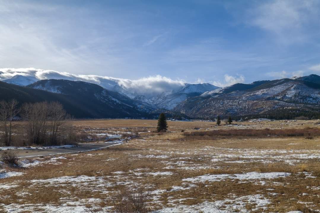 Vast valley with snow-dusted fields and distant mountains under cloudy sky. - Bear Lake loop from Estes Park
