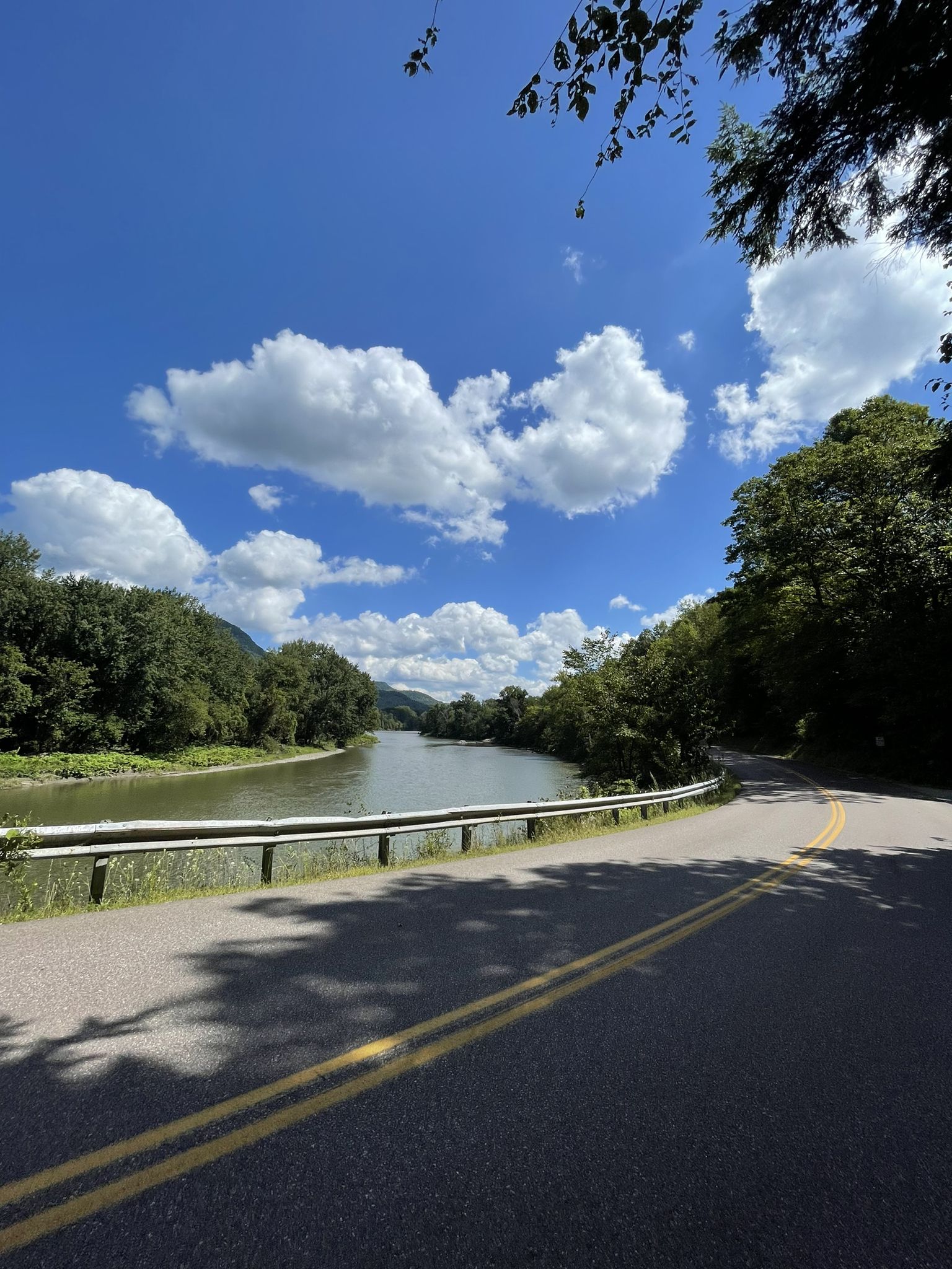 Curving road next to a river, green hills under a bright blue sky. - Church Converted into a Home – Waterbury loop from Richmond