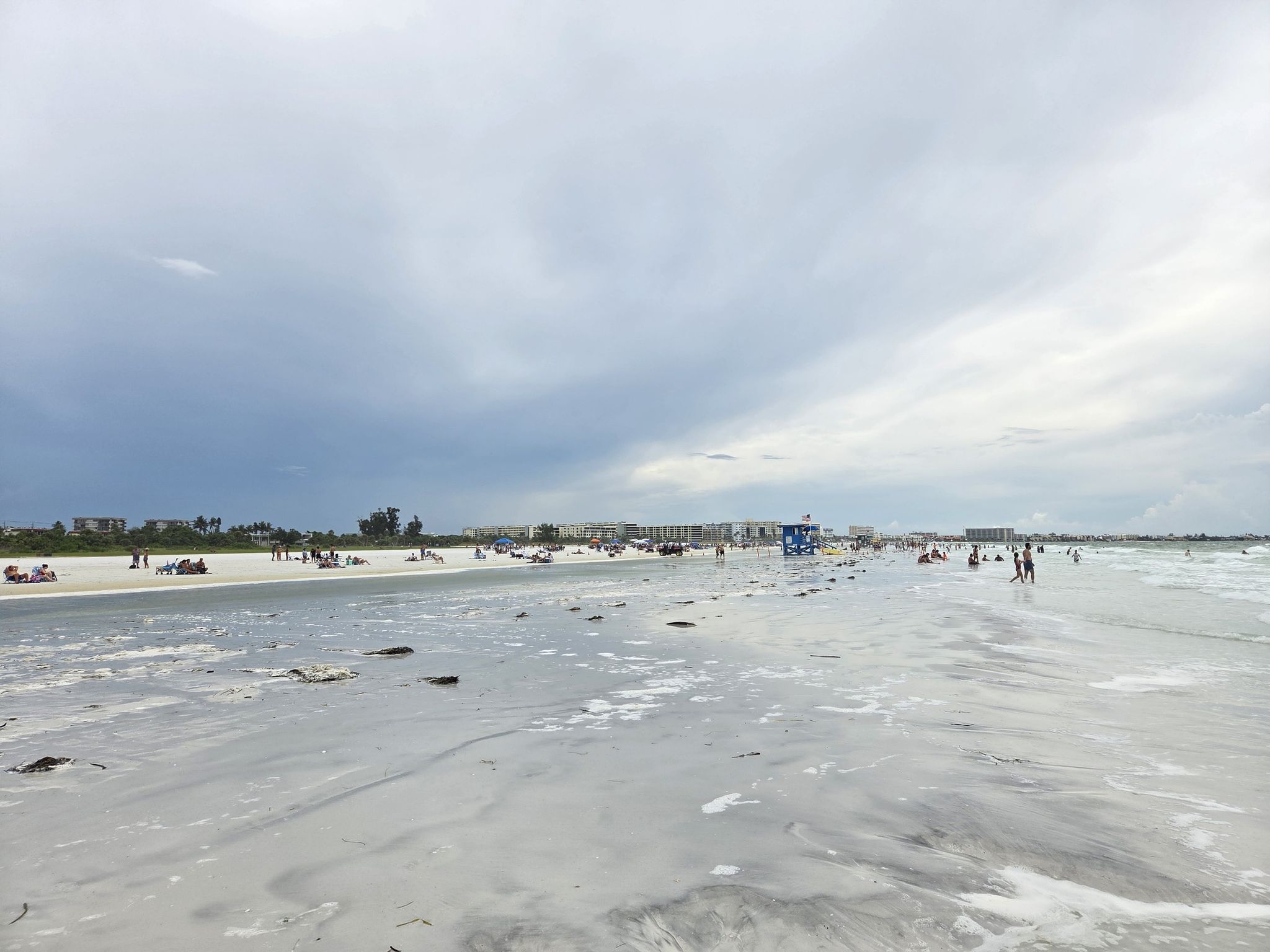 Wide, busy beach with many people, ocean waves, and distant buildings. - Running loop from Siesta Key