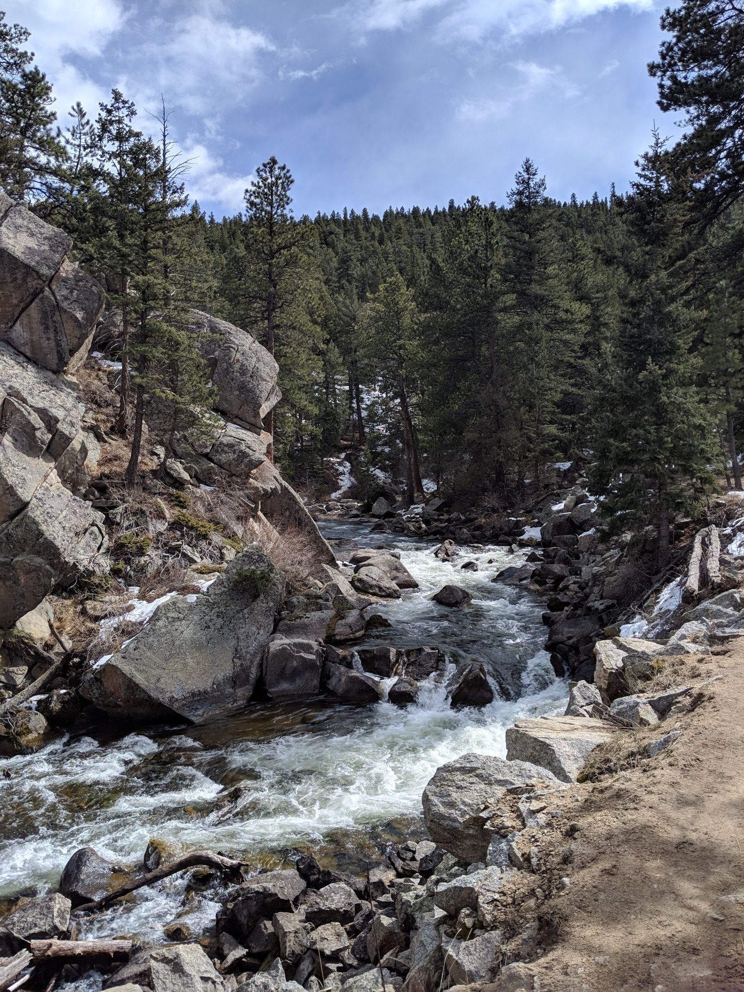 Rushing river cascades over rocks through a pine forest with snow patches. - South Boulder Creek via Walker Ranch Trail