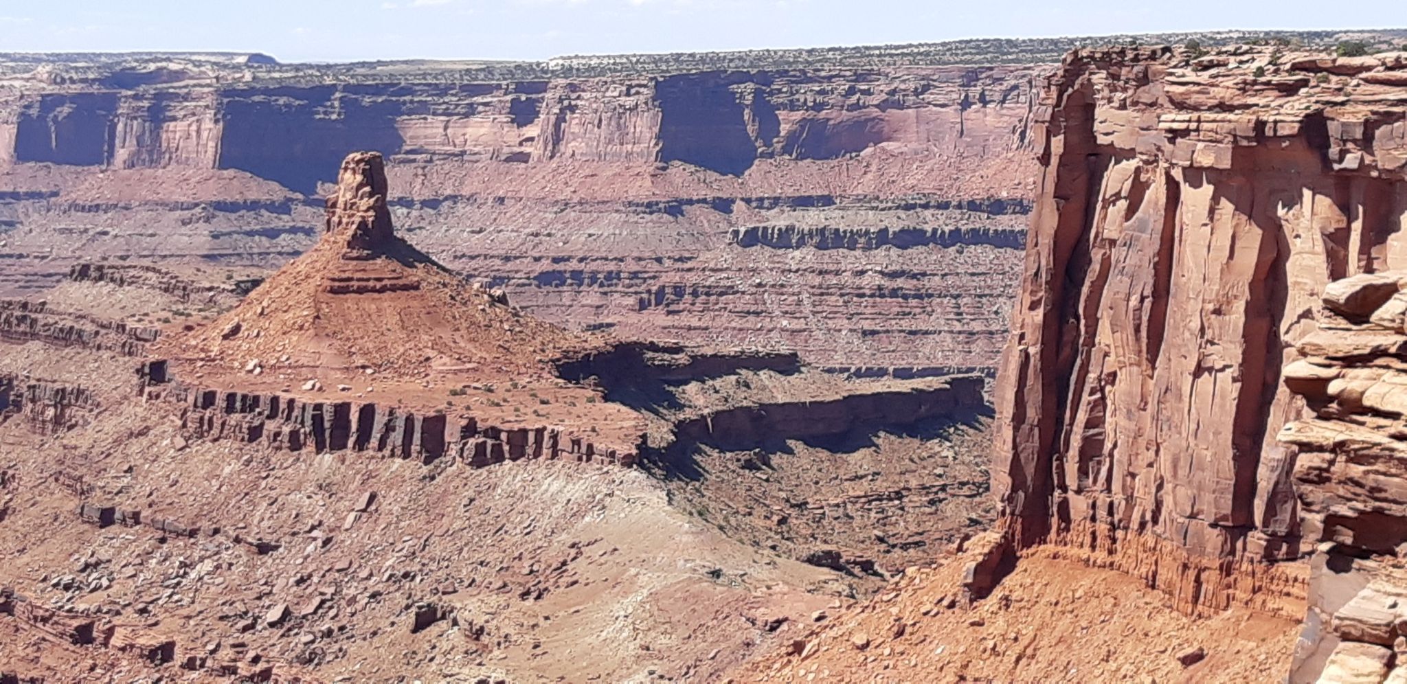 Prominent red rock formation in a deep canyon under bright sunlight. - West-Rim Trail – Meander Overlook loop from Dead Horse Point